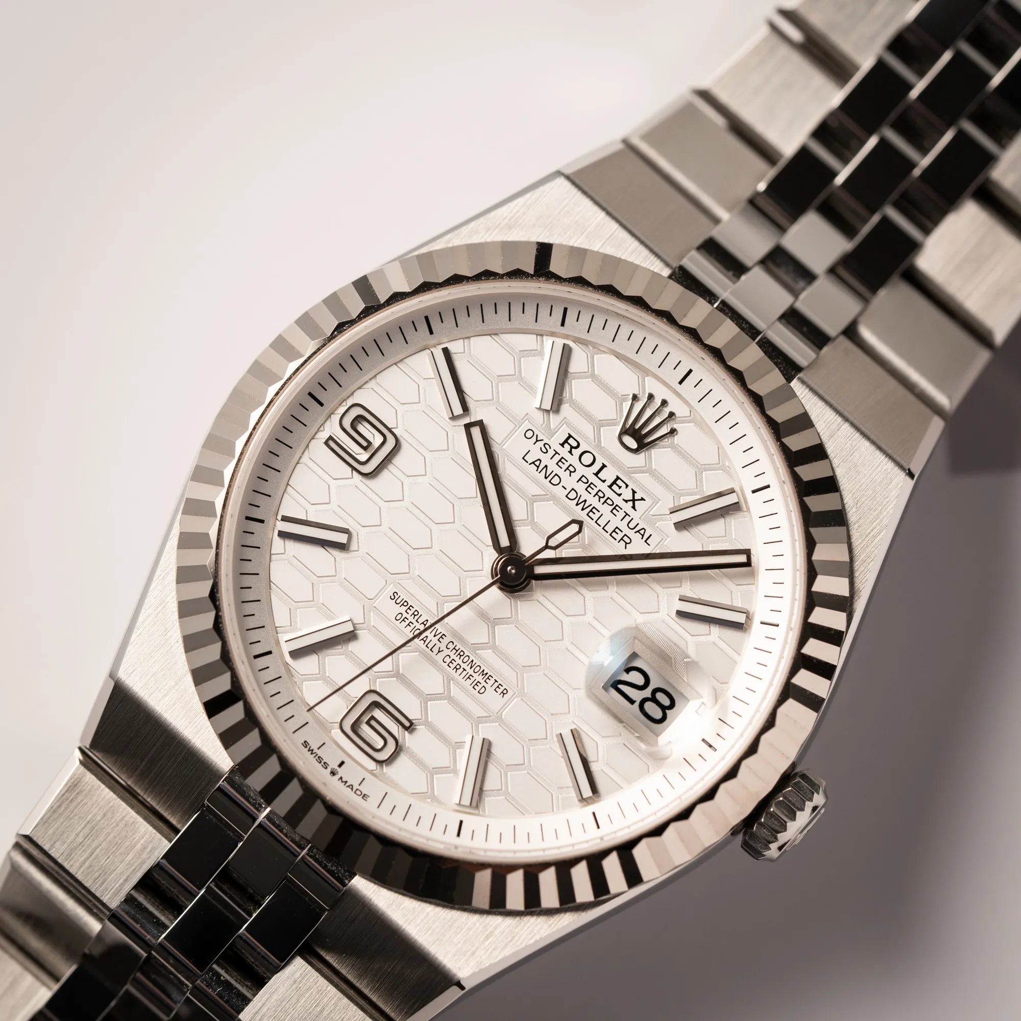 Nahaufnahme der Rolex Land-Dweller 40 der Referenz 127334 im neuwertigen Zustand mit dem weißen Zifferblatt in Waben-Struktur am neuen Flat-Jubilee-Armband