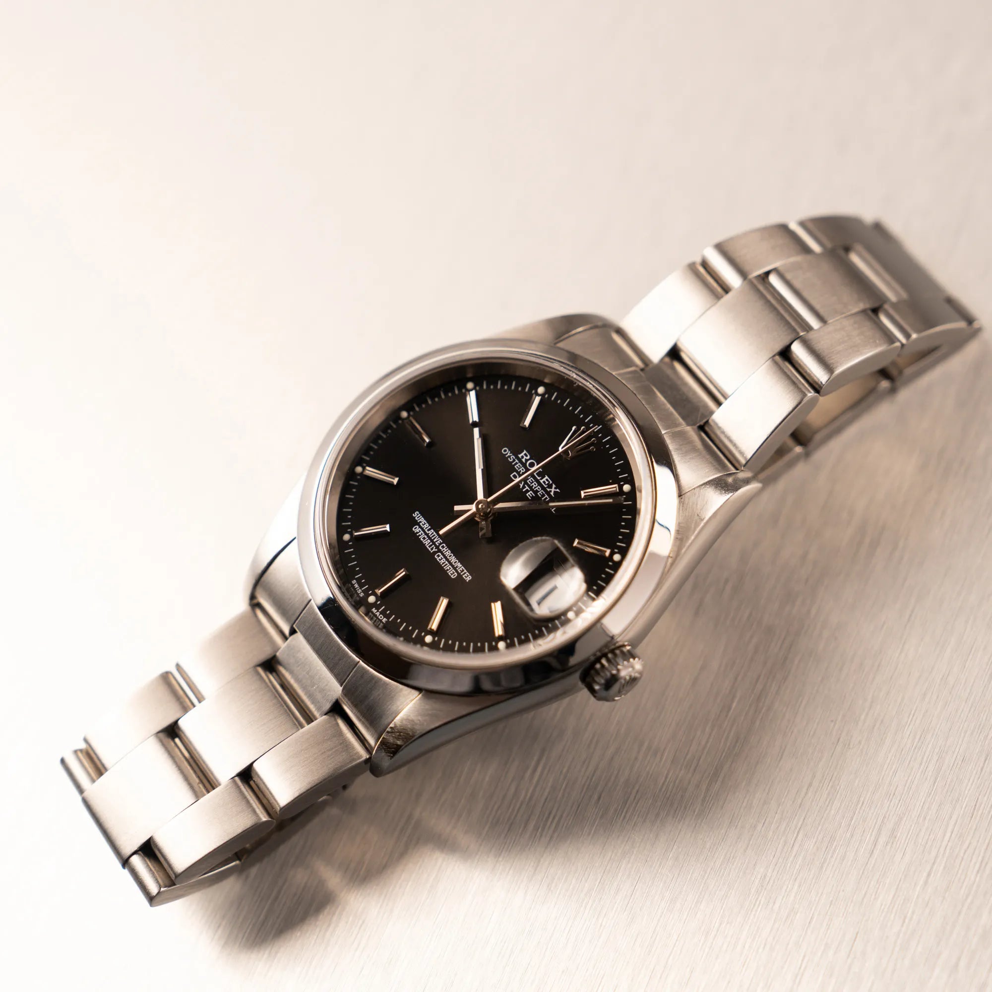 Produktfotografie der auf dem Band liegenden Rolex Oyster Perpetual 34 mit schwarzem Zifferblatt der Referenz 15200 mit glatter Lünette und 34mm Gehäusedurchmesser