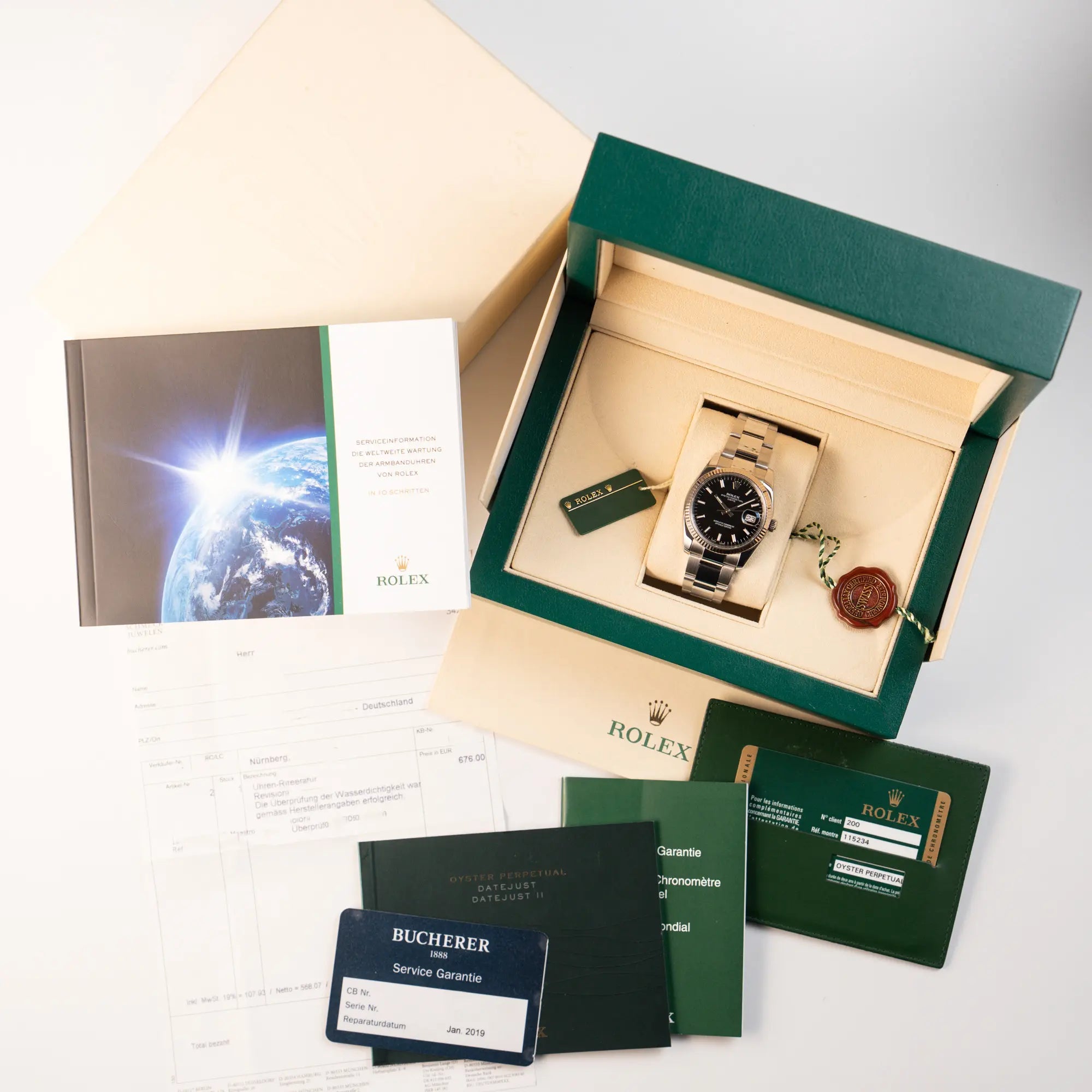 Rolex Oyster Perpetual Date 34 der Referenz 115234 mit schwarzem Zifferblatt und der geriffelten Weißgold-Lünette  zusammen mit dem Lieferumfang, bestehend aus Box, Umkarton, Booklets, Garantiekarte, Service-Beleg und Hangatag