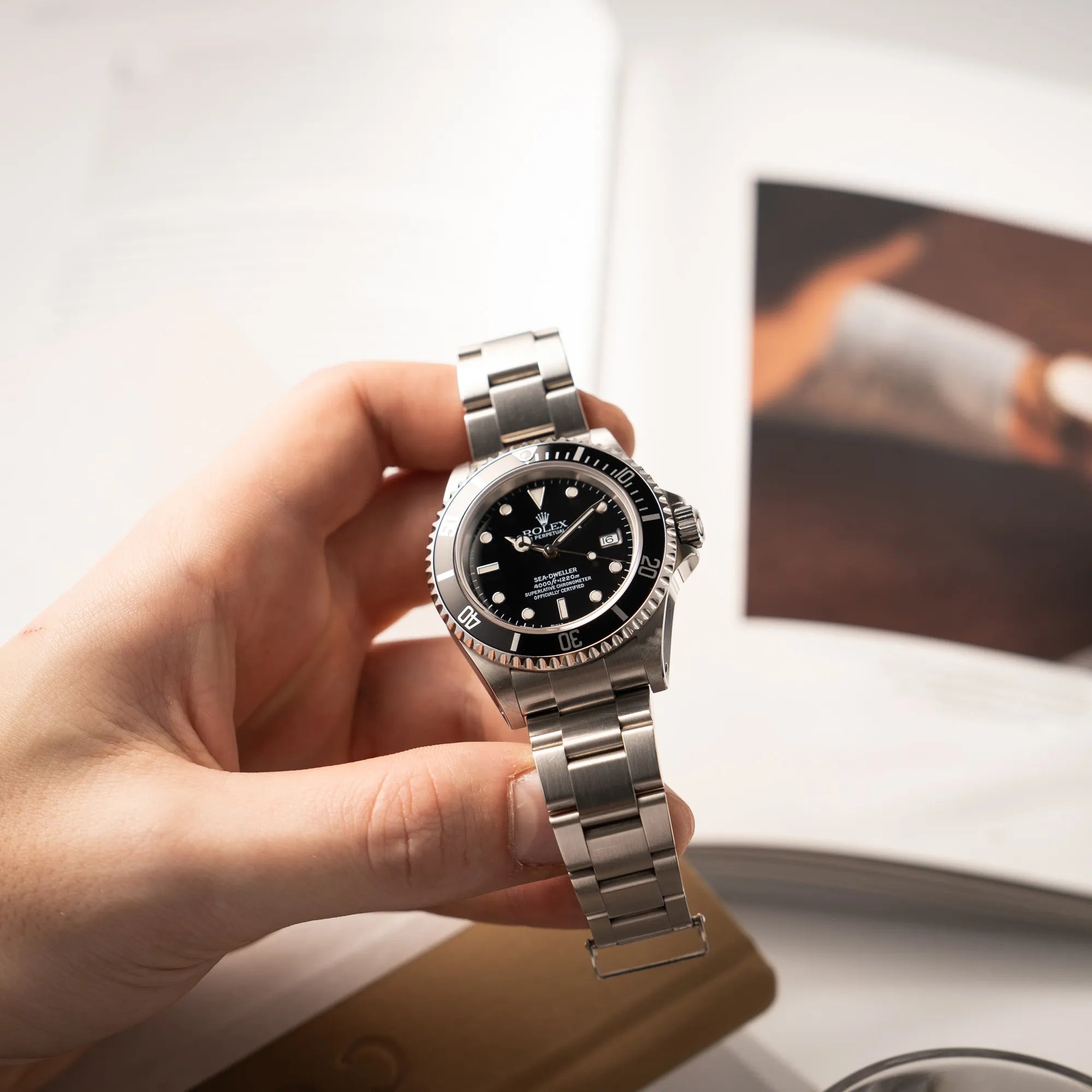Mann hält die Rolex Sea-Dweller  mit schwarzem Zifferblatt und schwarzer Aluminium-Lünetten-Einlage der Referenz 16600 aus 2000 in seiner Hand und präsentiert die Uhr in die Kamera