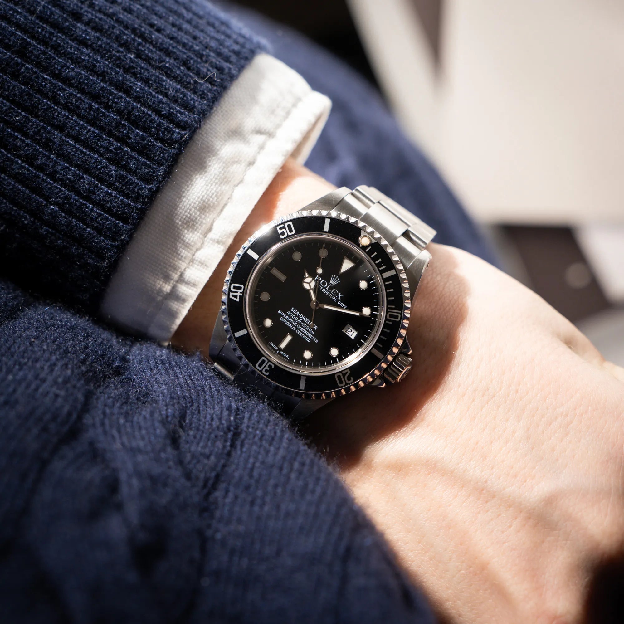 Mann trägt die Rolex Sea-Dweller 4000 der Referenz 16600 mit der klassischen schwarzen Aluminium-Lünette aus Dezember 2002 an seinem Handgelenk