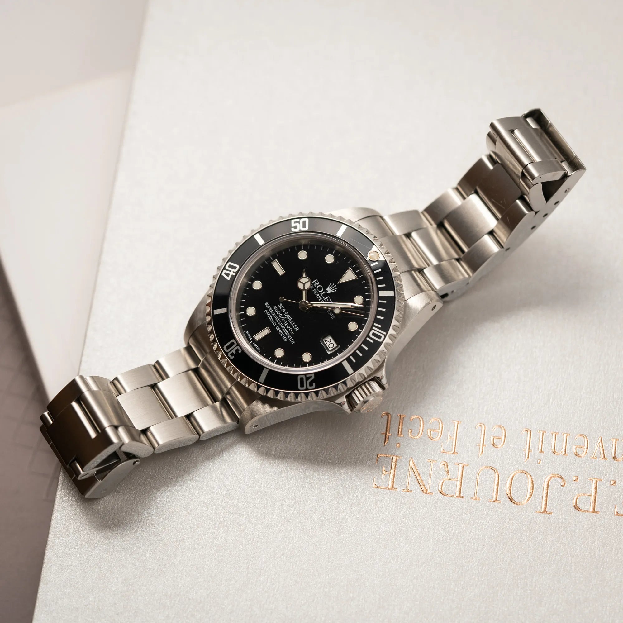 Rolex Sea-Dweller 4000 der Referenz 16600 mit der klassischen schwarzen Aluminium-Lünette aus Dezember 2002 liegt flach auf einem Buch