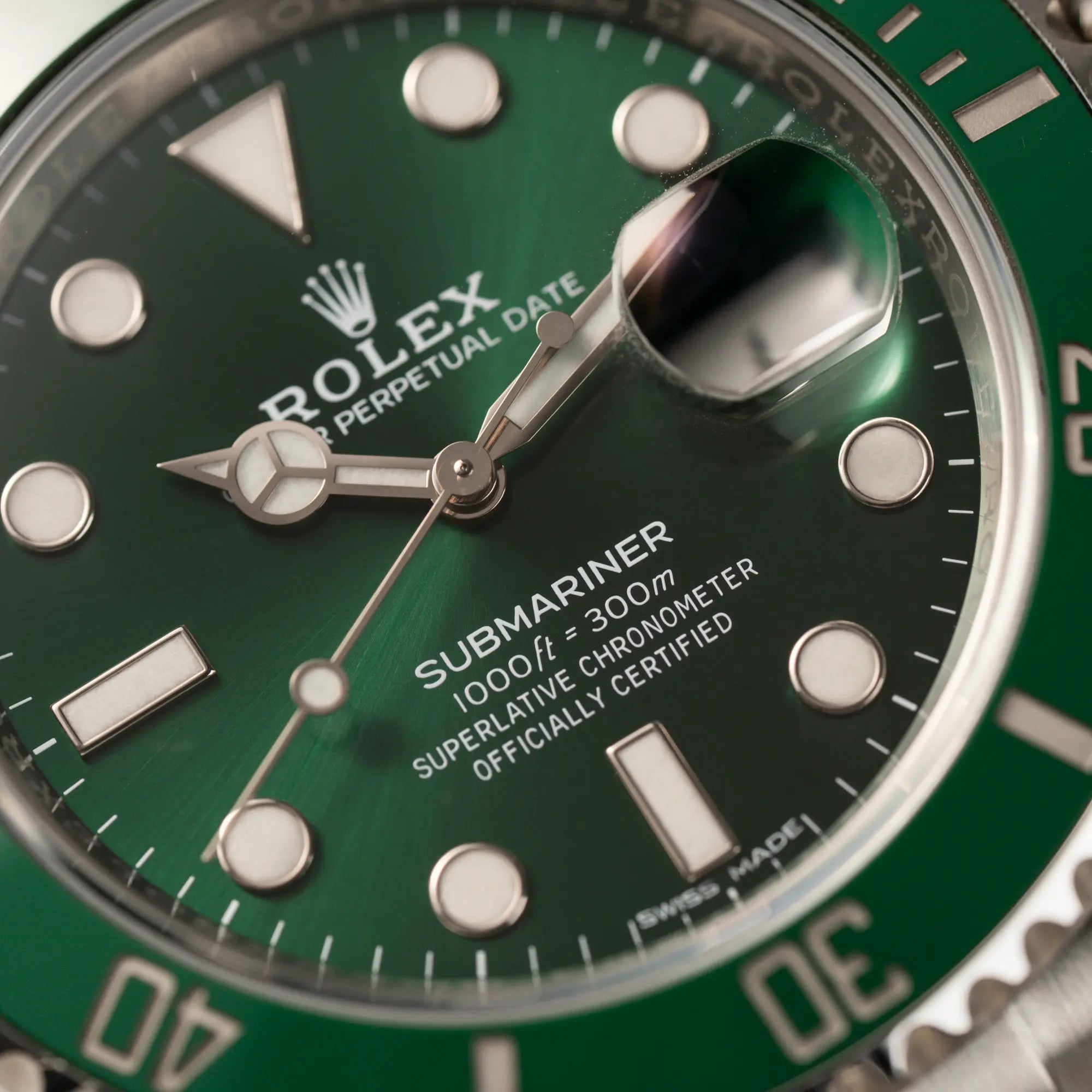 Makroaufnahme der Rolex Submariner Date 116610LV "Hulk" mit grünem Zifferblatt und grüner Keramik-Lünette mit Fokus auf dem Zeigersatz