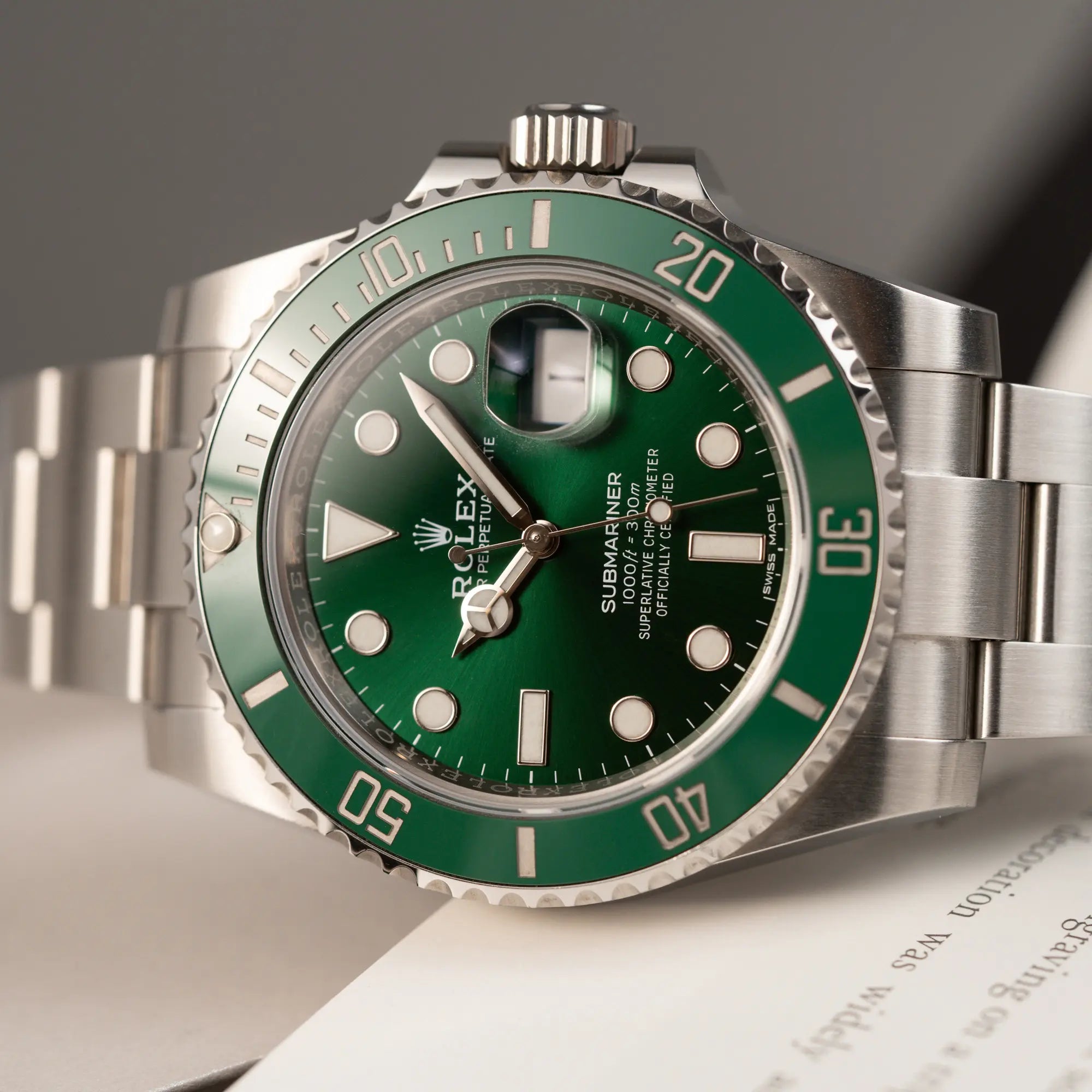Detailaufnahme der seitlich auf dem Uhrengehäuse liegenden Rolex Submariner Date 116610LV "Hulk" mit grünem Zifferblatt und grüner Keramik-Lünette