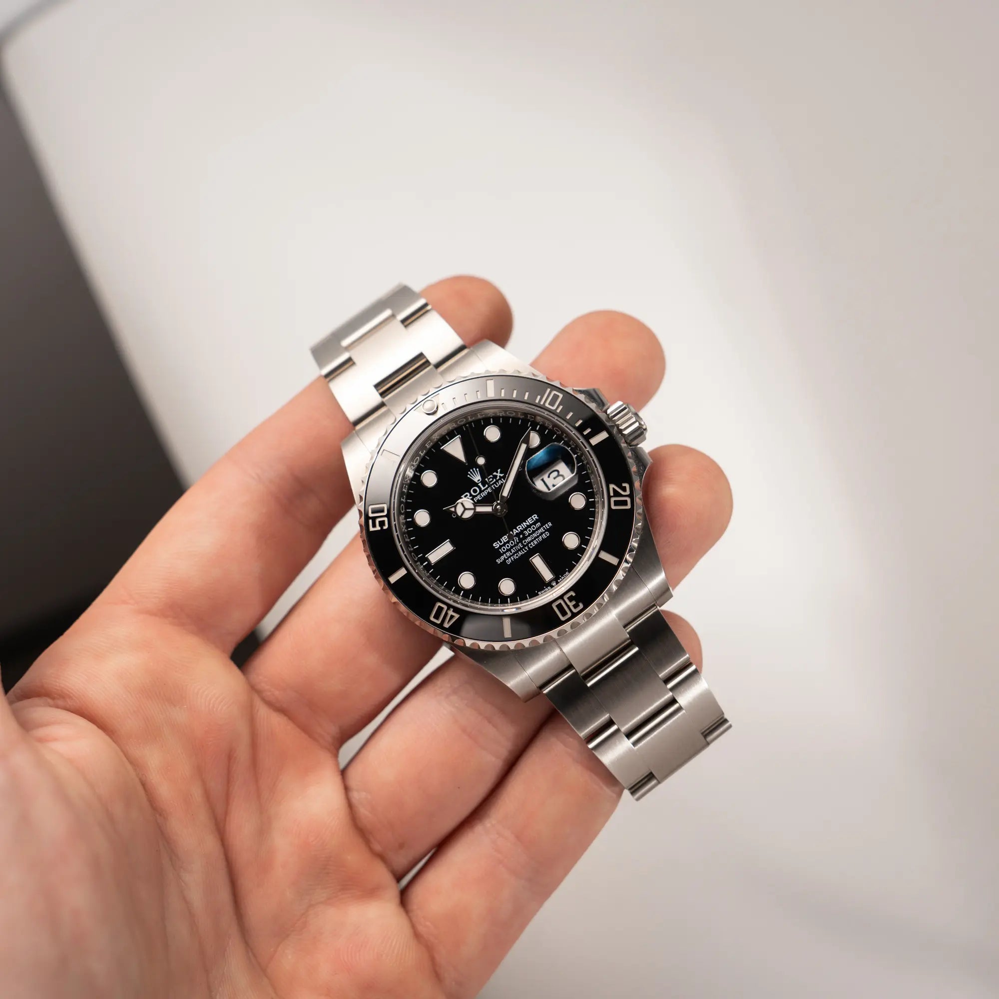 Mann hält die Rolex Submariner Date in schwarz mit Keramik-Lünette  am Oyster-Stahlband aus 2023 mit dem 41mm-Oyster-Gehäuse in seiner Hand und präsentiert die Uhr in die Kamera