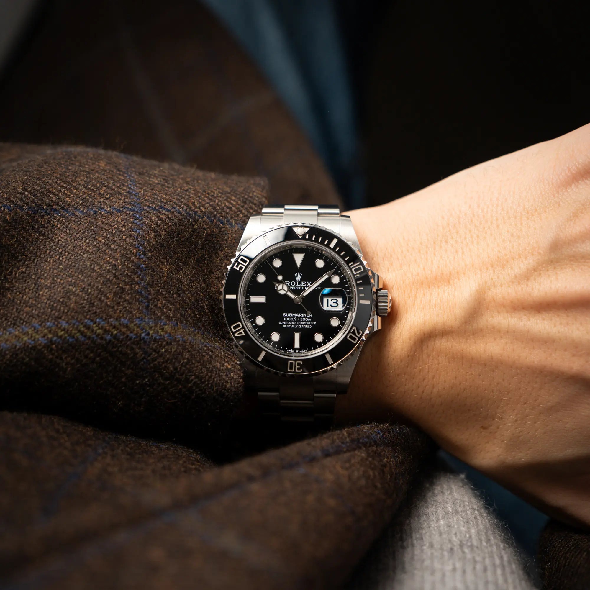 Mann in braunem Sakko trägt die Rolex Submariner Date in schwarz mit Keramik-Lünette  am Oyster-Stahlband aus 2023 mit dem 41mm-Oyster-Gehäuse