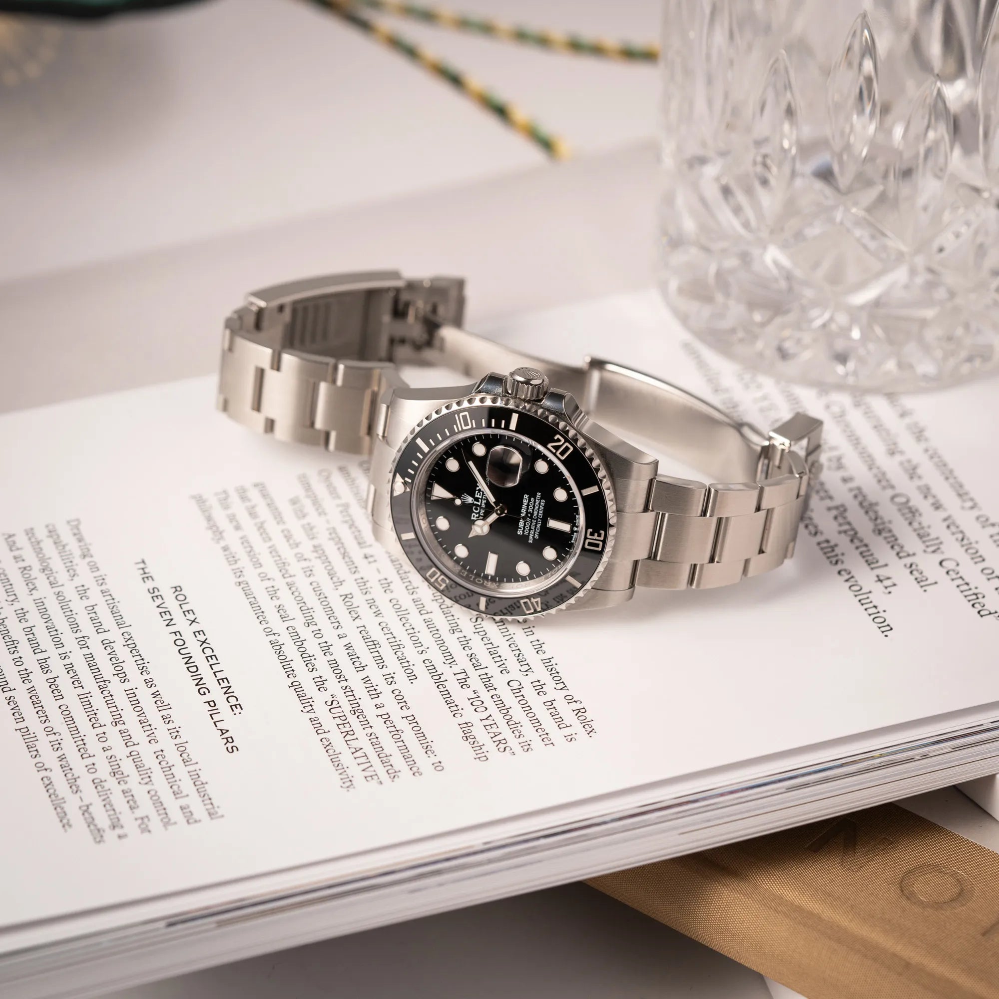 Rolex Submariner Date 126610LN am Oyster-Stahlband im Neuzustand aus 2024 liegt mit geöffneter Faltschliesse auf einem Rolex-Magazin