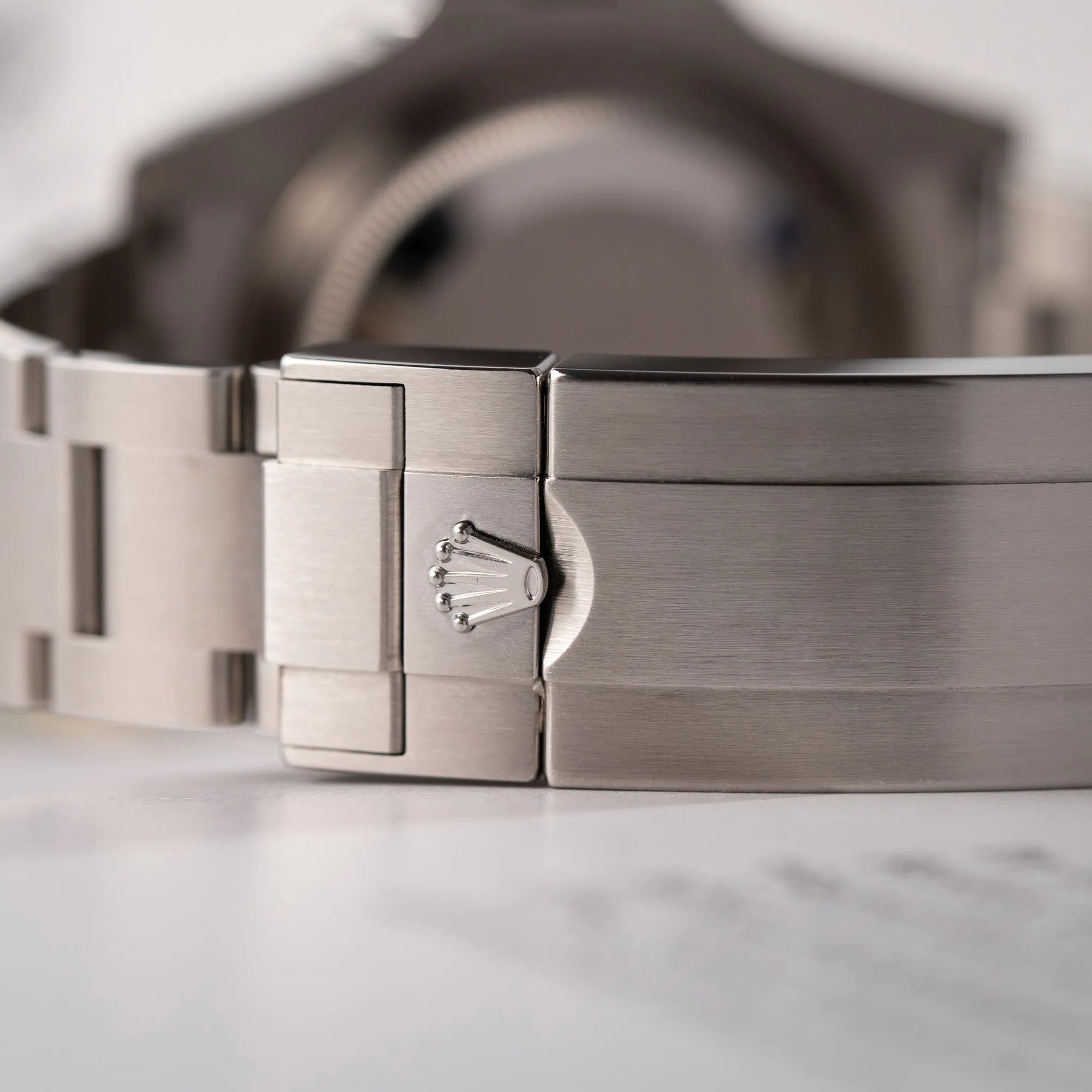 Detailaufnahme der Rolex-Krone auf der Oyster-Stahl-Schliesse der Rolex Submariner Date 126610LN am Oyster-Stahlband im Neuzustand aus 2024