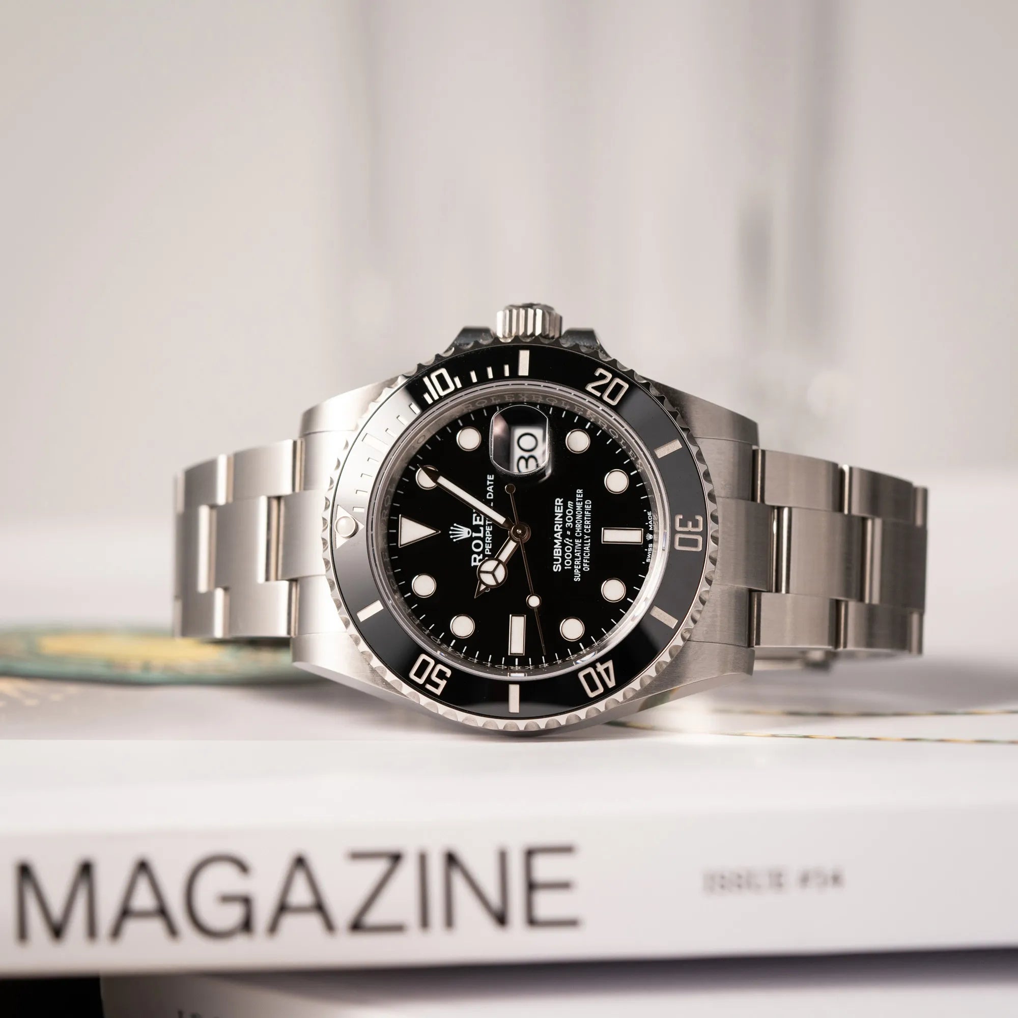 Produktfotografie der seitlich auf dem Uhrengehäuse liegenden Rolex Submariner Date 126610LN am Oyster-Stahlband im Neuzustand
