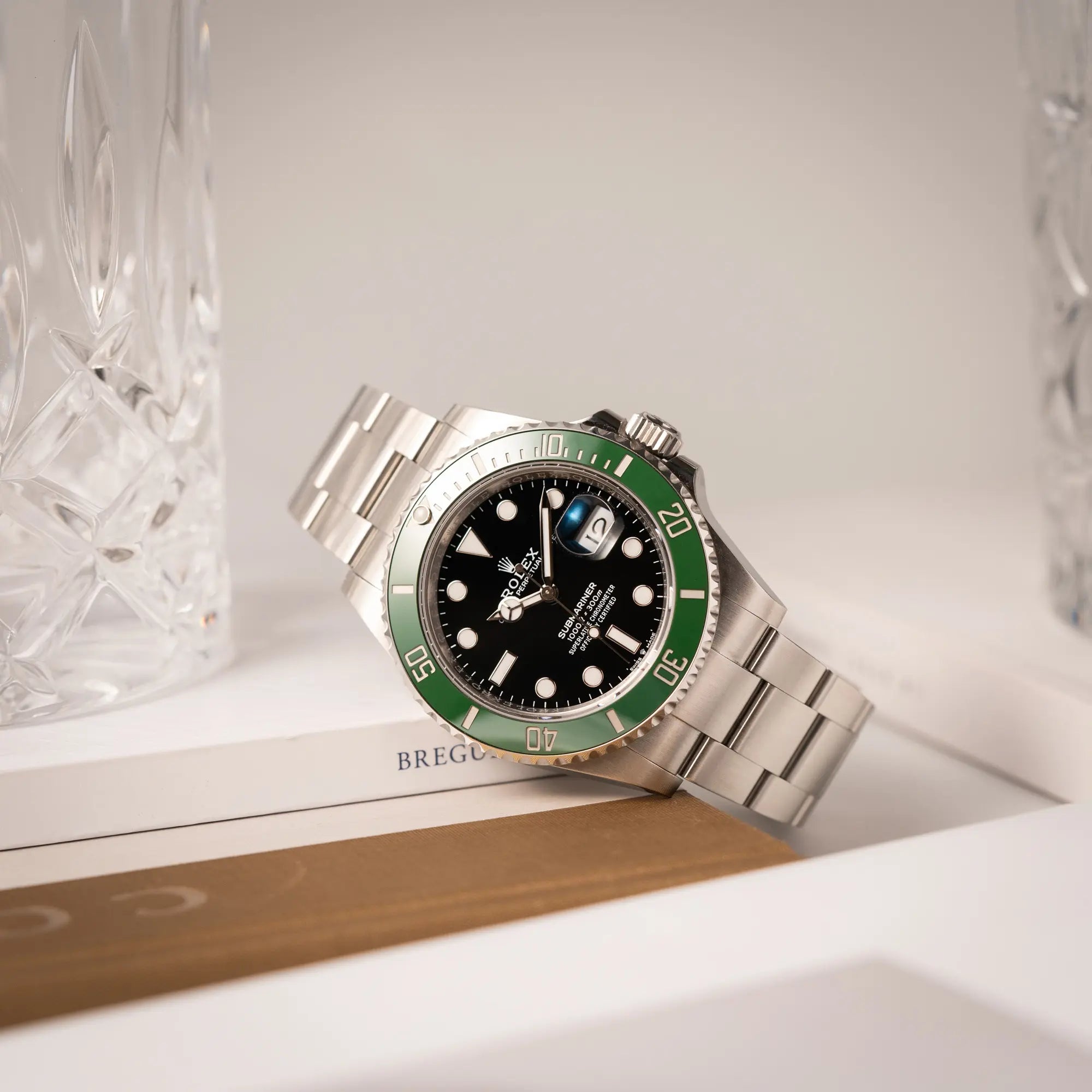 Rolex Submariner Date 126610LV, Nickname "Starbucks", mit schwarzem Zifferblatt und grüner Keramik-Lünette in der MK2-Ausführung am Oyster-Stahl-Band lehnt an einem Buch