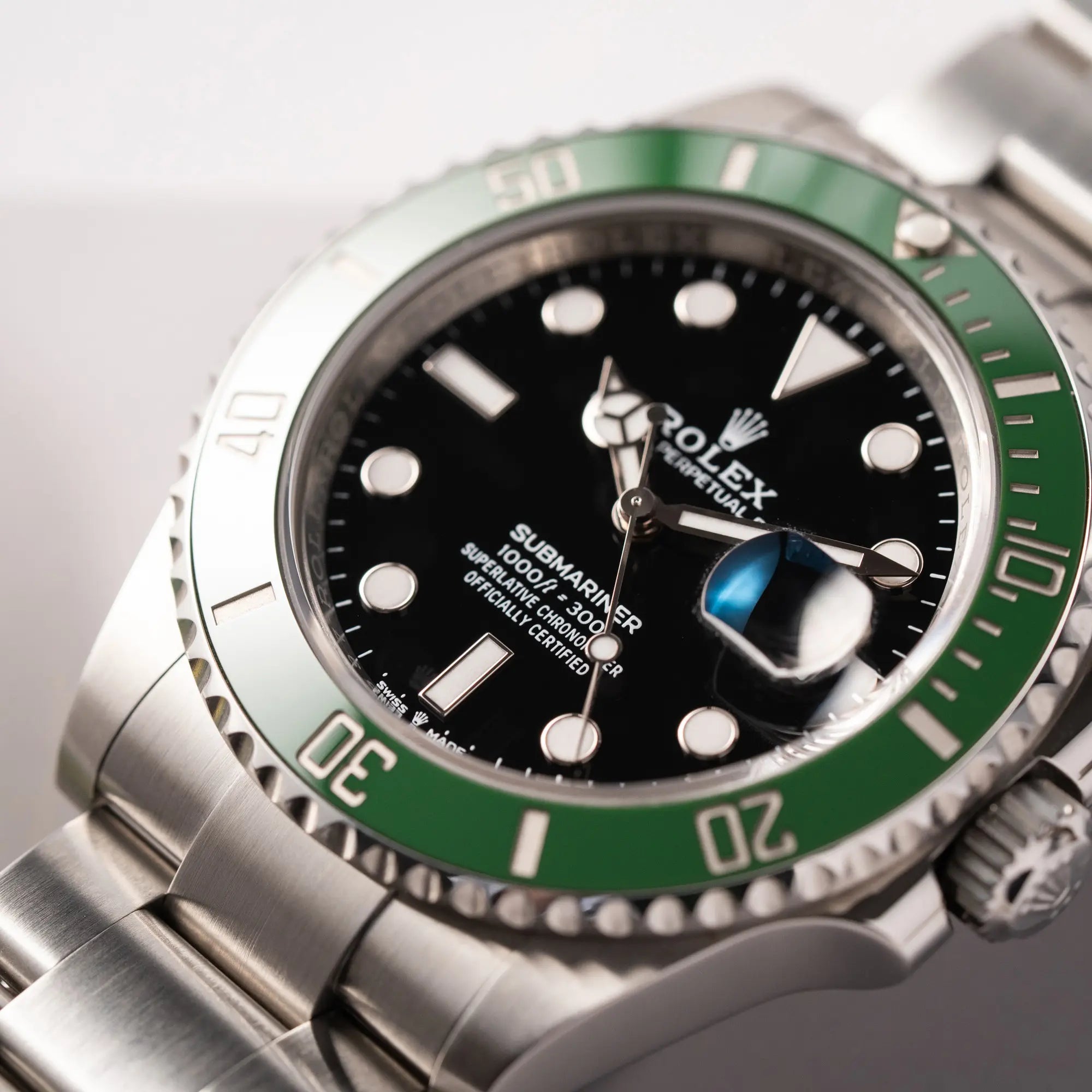 Detailaufnahme mit Fokus auf dem Submariner-Schriftzug von der Rolex Submariner Date 126610LV, Nickname "Starbucks", mit schwarzem Zifferblatt und grüner Keramik-Lünette in der MK2-Ausführung am Oyster-Stahl-Band