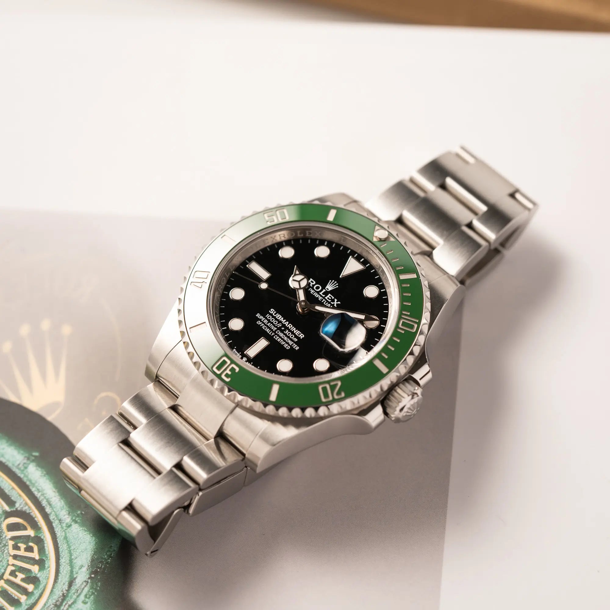 Rolex Submariner Date 126610LV, Nickname "Starbucks", mit schwarzem Zifferblatt und grüner Keramik-Lünette in der MK2-Ausführung am Oyster-Stahl-Band liegt auf einem Rolex-Magazin