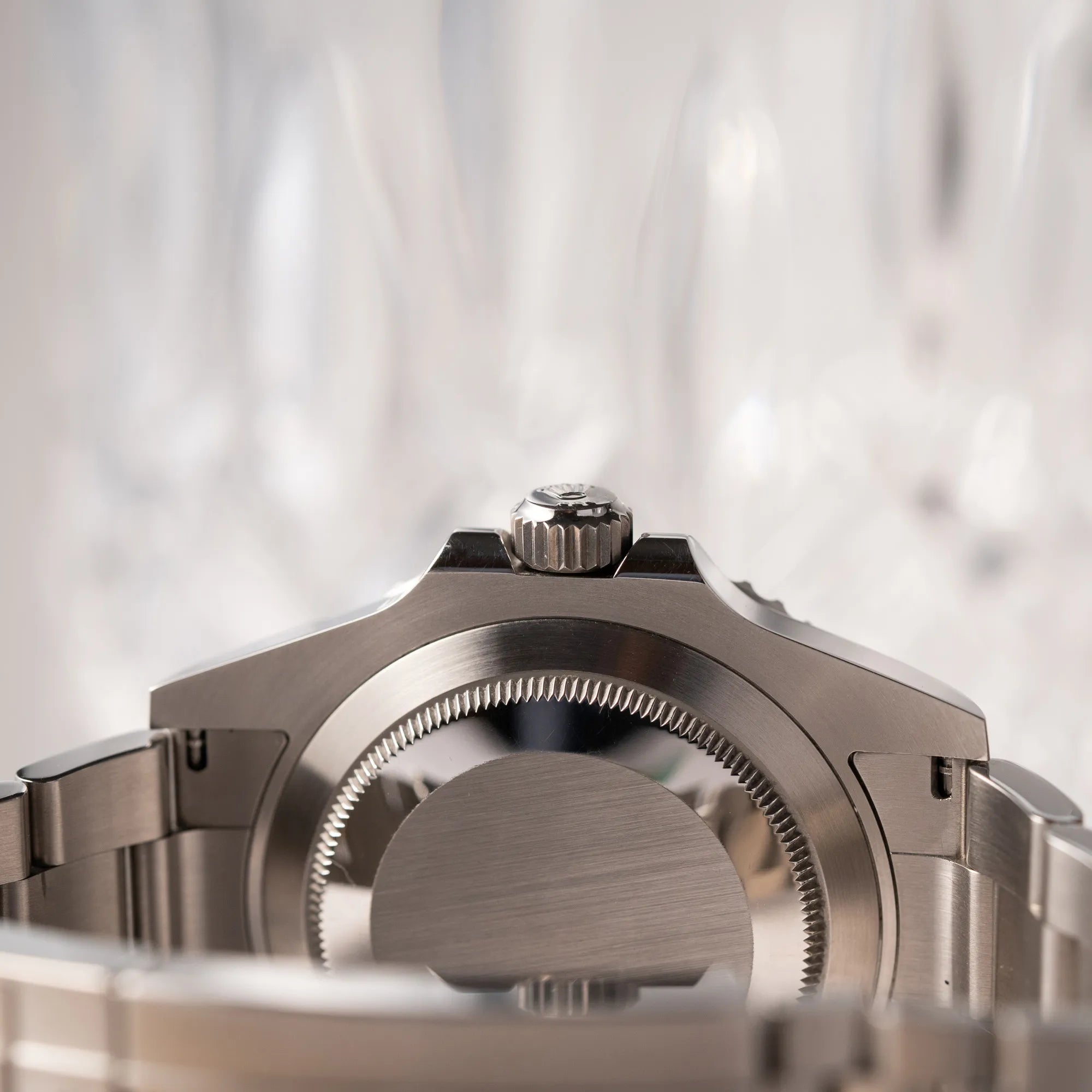 Produktfotografie zeigt den Gehäuseboden und die Aufzugskrone von der Rolex Submariner Date 126610LV, Nickname "Starbucks", mit schwarzem Zifferblatt und grüner Keramik-Lünette in der MK2-Ausführung am Oyster-Stahl-Band