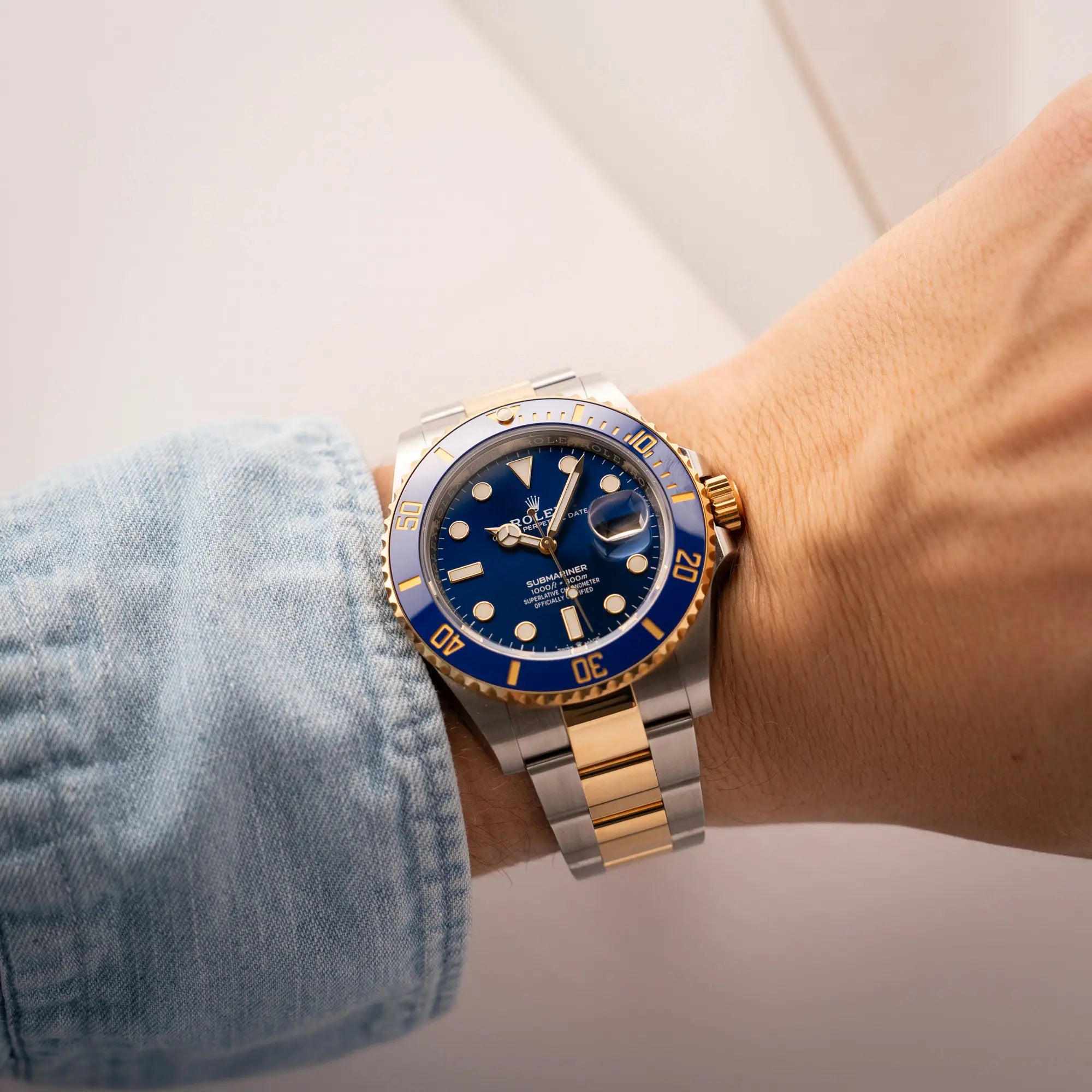 Mann trägt die Rolex Submariner Date 126613LB Bluesy mit der typischen Kombination aus blauem Zifferblatt und Lünette mit dem Gehäuse und Armband aus Stahl-Gold für einen Wristshot an seinem Handgelenk