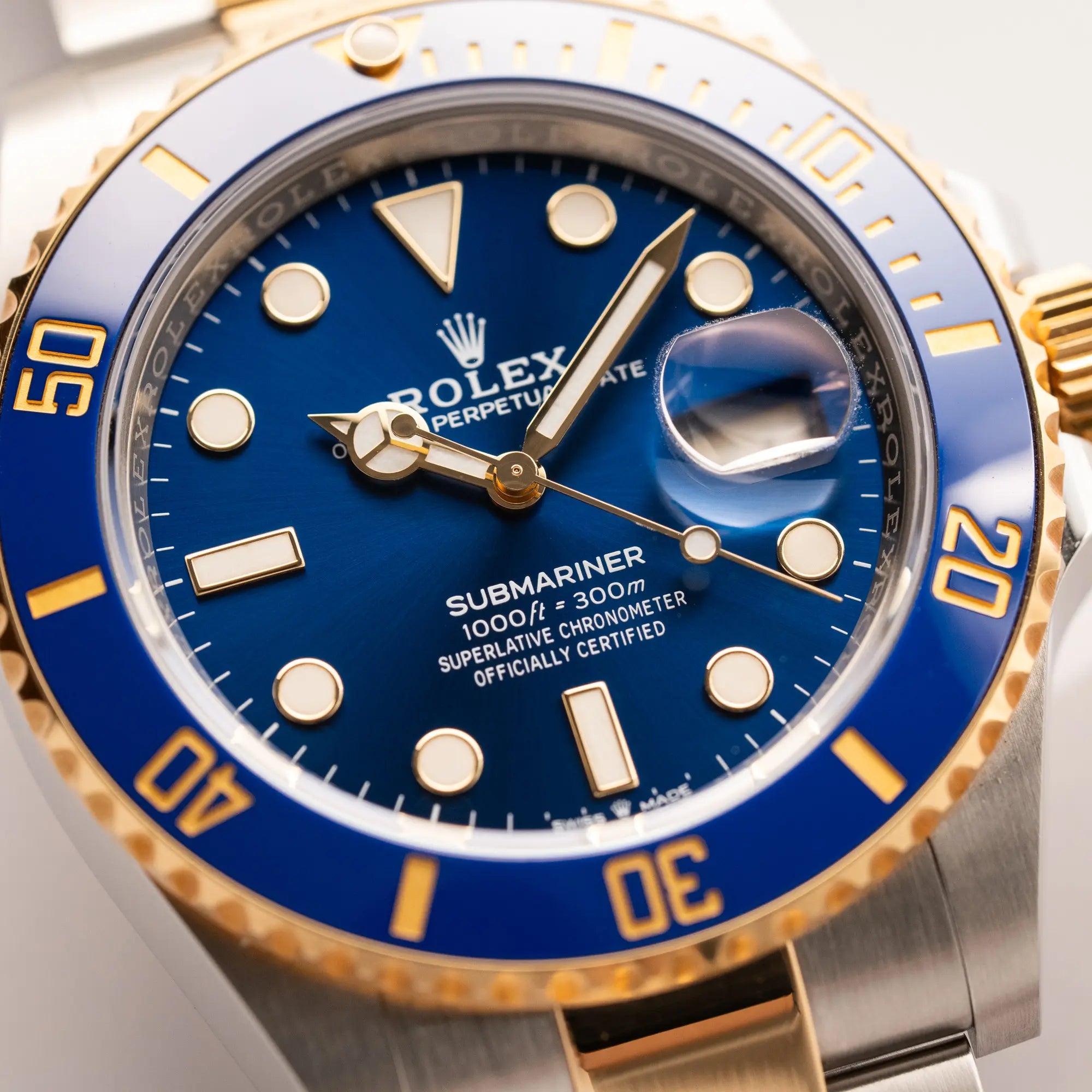 Detailaufnahme zeigt das Sonnenschliff-Zifferblatt mit weißen Details von der Rolex Submariner Date 126613LB Bluesy mit der typischen Kombination aus blauem Zifferblatt und Lünette mit dem Gehäuse und Armband aus Stahl-Gold