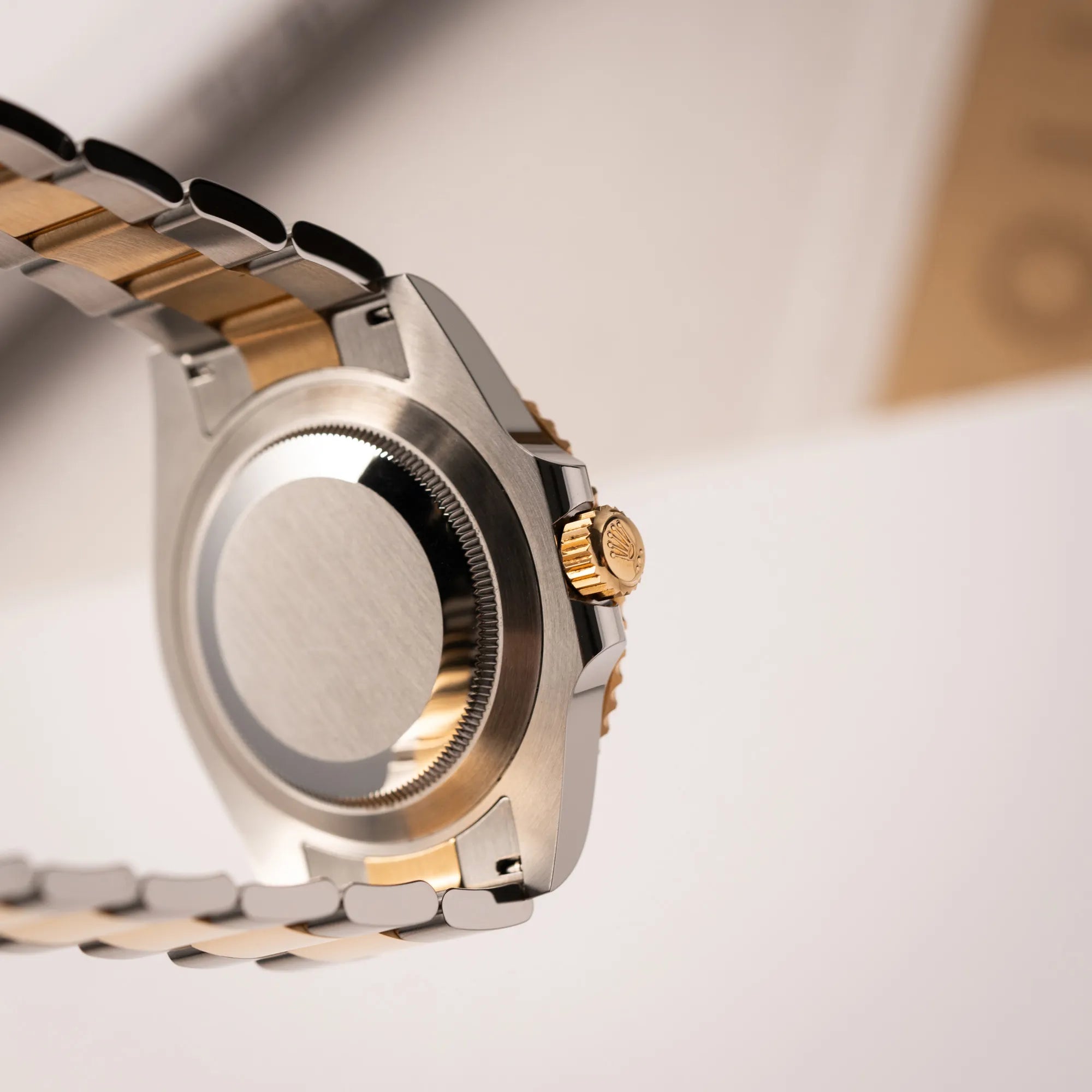 Blick auf den Gehäuseboden und die goldene Aufzugskrone der Rolex Submariner Date 126613LB Bluesy mit der typischen Kombination aus blauem Zifferblatt und Lünette mit dem Gehäuse und Armband aus Stahl-Gold