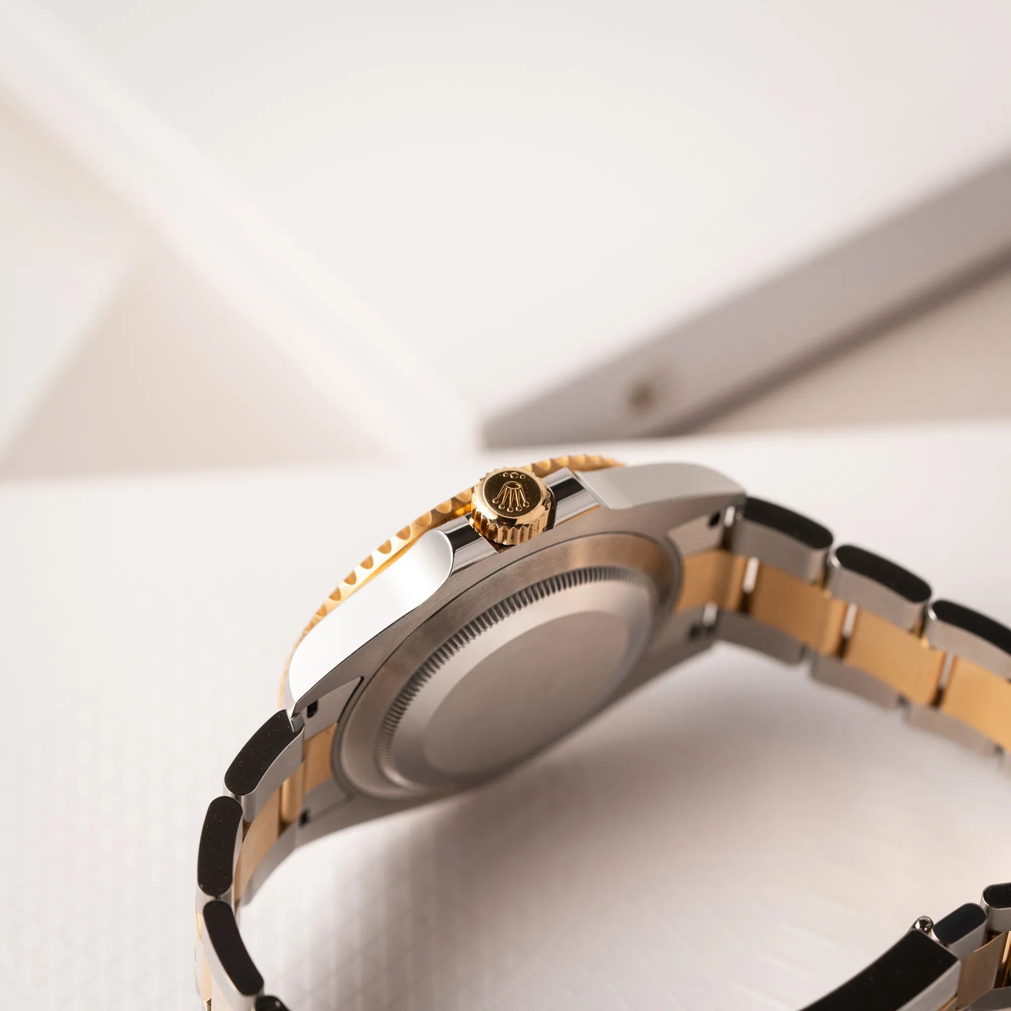 Produktfotografie der Rolex Submariner Date 126613LB Bluesy mit der typischen Kombination aus blauem Zifferblatt und Lünette mit dem Gehäuse und Armband aus Stahl-Gold zeigt die seitliche Gehäuseflanke mit Blick auf die goldenen Aufzigskrone