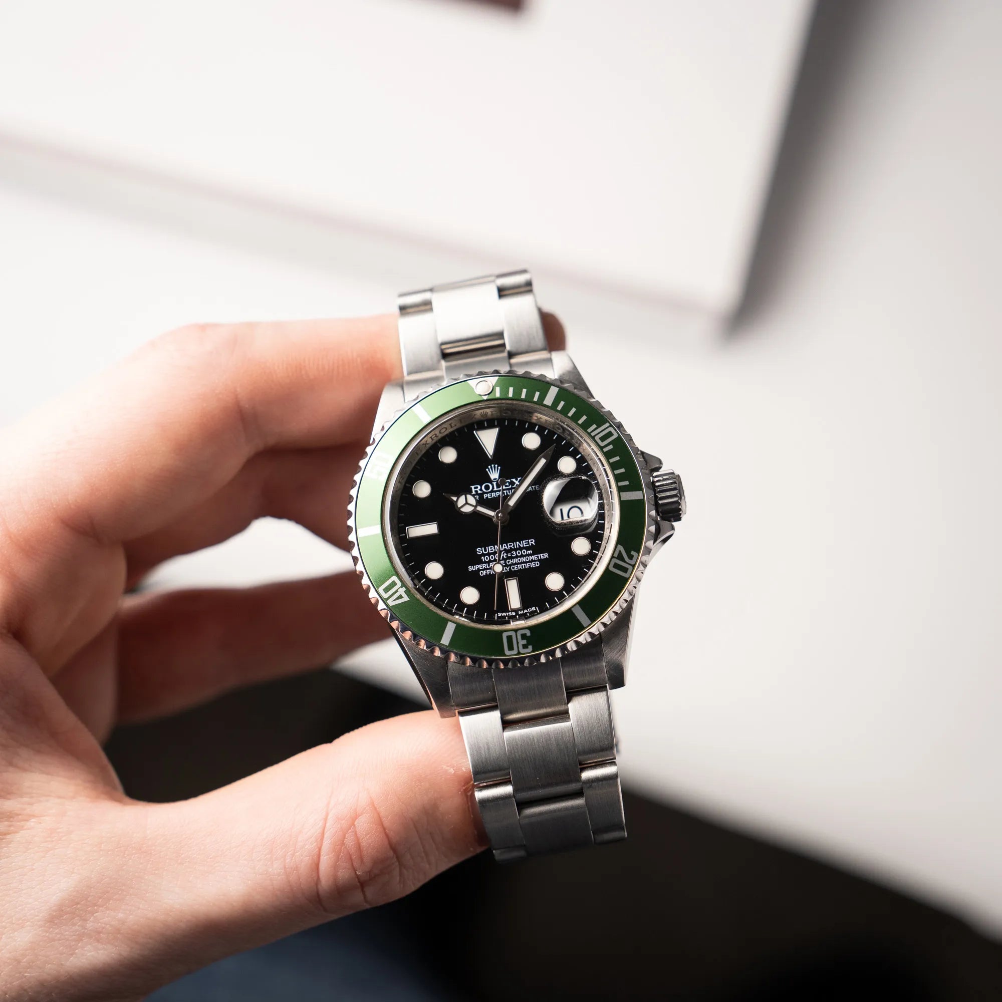 Mann hält die Rolex Submariner Date 16610LV mit der grünen Aluminium-Lünetten-Einlage und präsentiert die Uhr in die Kamera