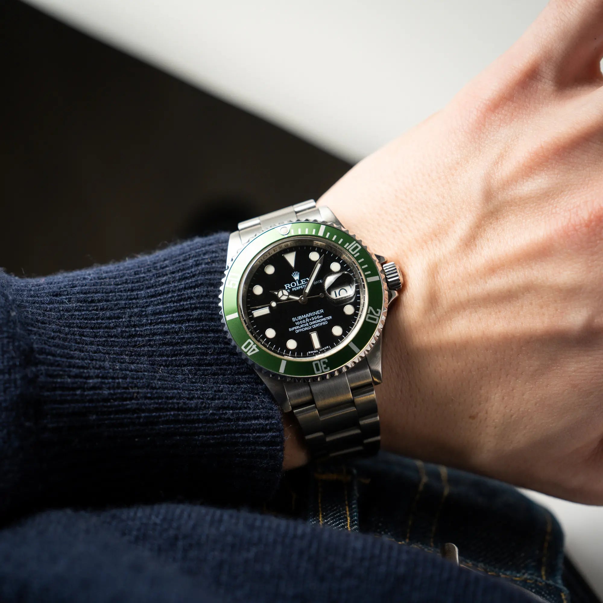 Mann trägt die Rolex Submariner Date 16610LV mit der grünen Aluminium-Lünetten-Einlage für einen Wristshot an seinem Handgelenk