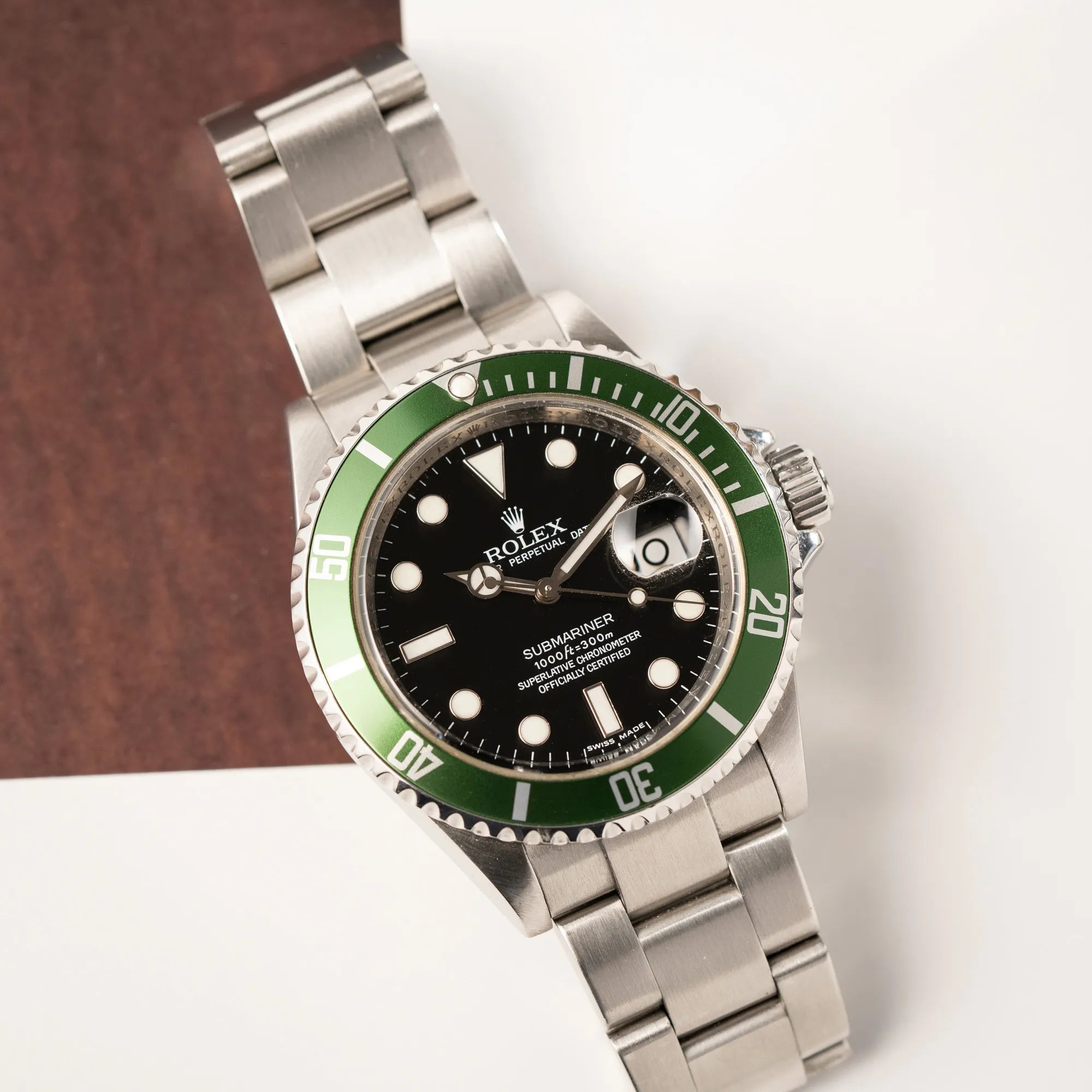 Produktfotografie zeigt die Rolex Submariner Date 16610LV mit der grünen Aluminium-Lünetten-Einlage aus der Vogelpersperspektive