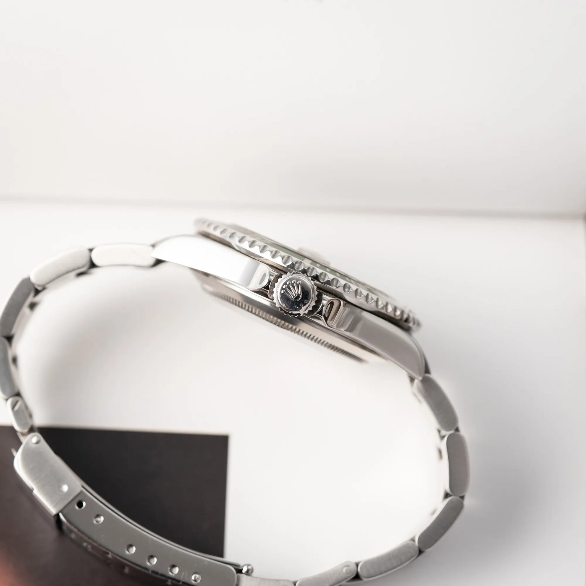 Produktfotografie der Rolex Submariner Date 16610LV mit der grünen Aluminium-Lünetten-Einlage zeigt die seitliche Gehäuseflanke mit Blick auf die Aufzugskrone