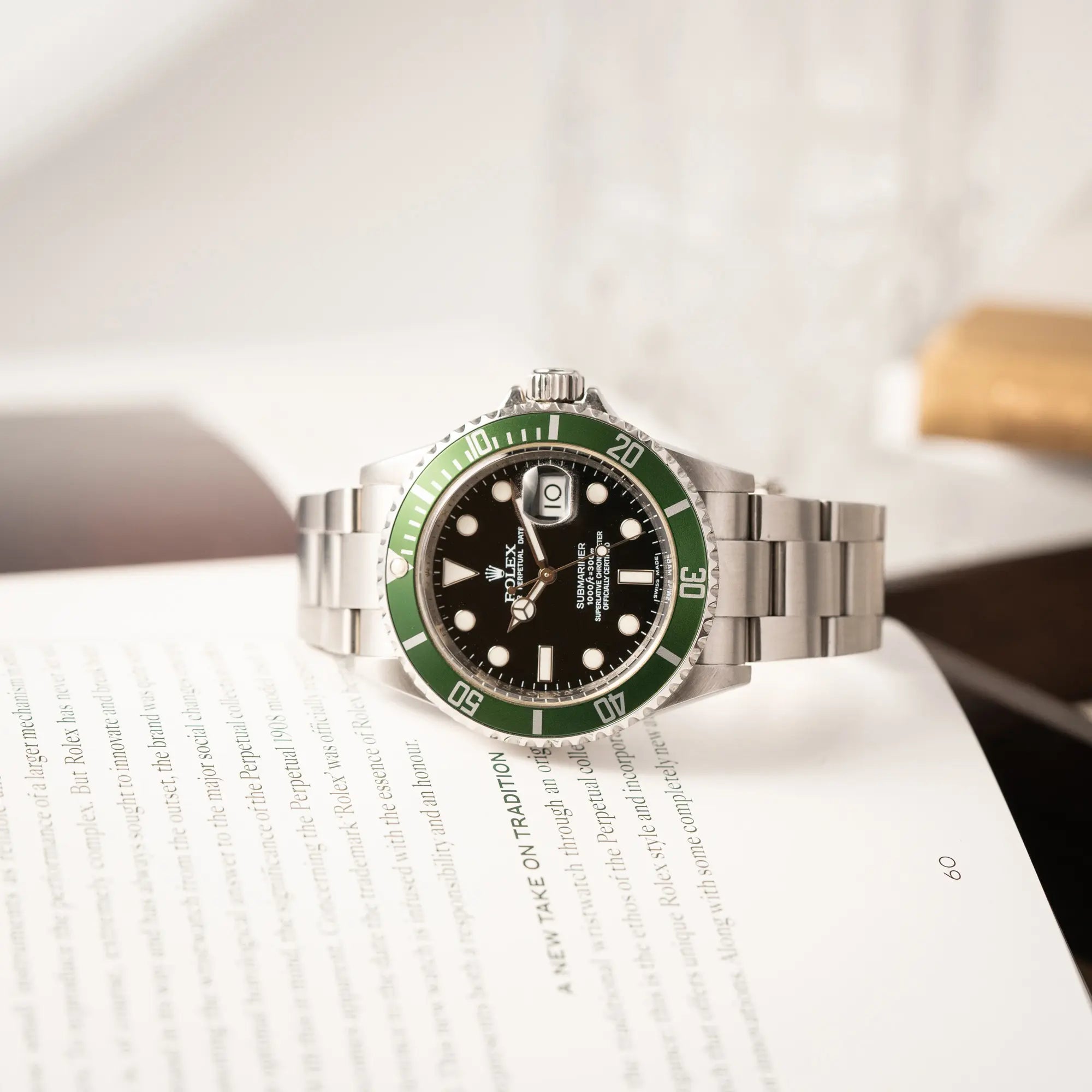 Rolex Submariner Date 16610LV mit der grünen Aluminium-Lünetten-Einlage liegt auf der eigenen seitlichen Gehäuseflanke