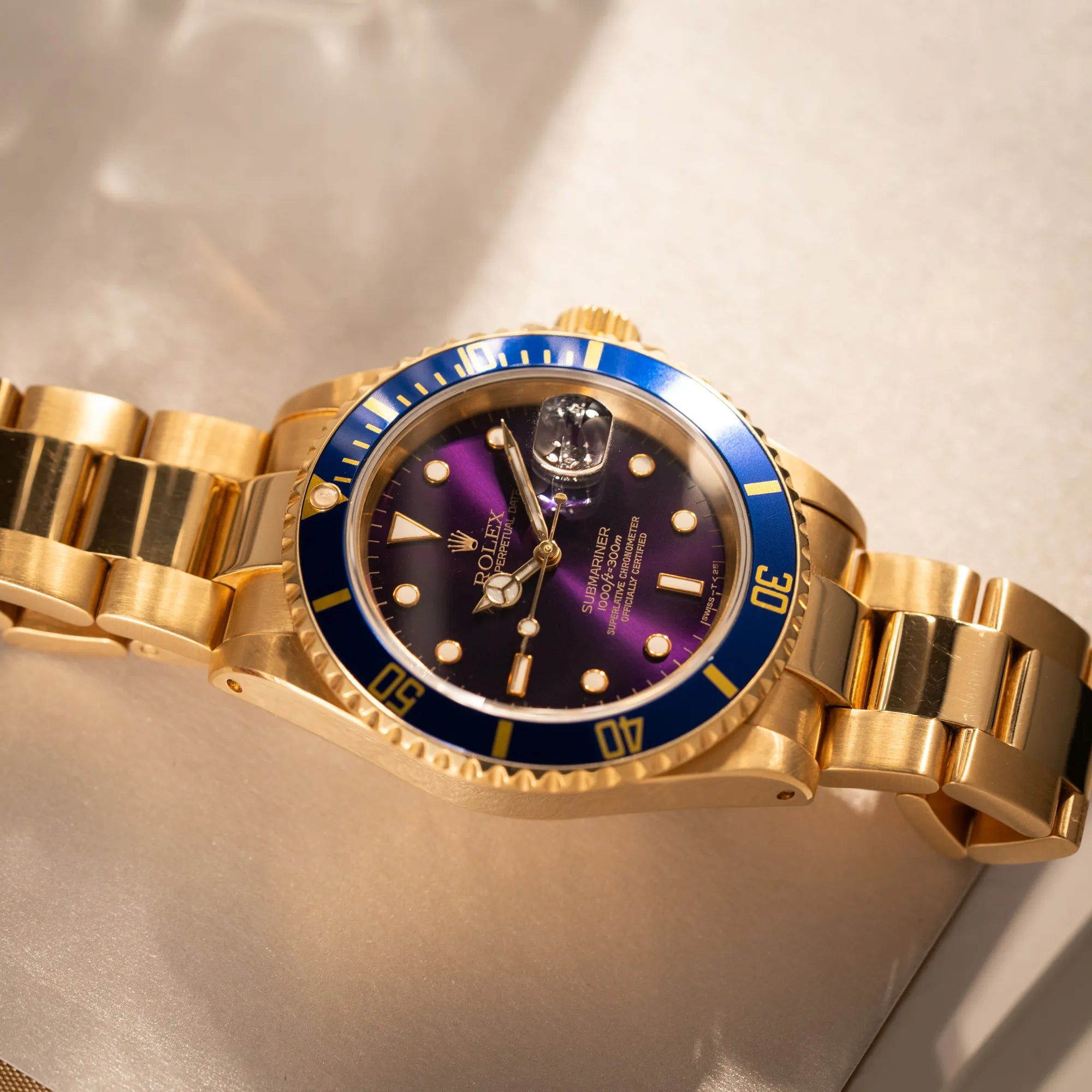 Produktfotografie der Rolex Submariner Date 16618 aus 18Karat Gelbgold mit blauer Lünetten-Einlage und einem sich von BLAU zu LILA verfärbtem Purple-Zifferblatt
