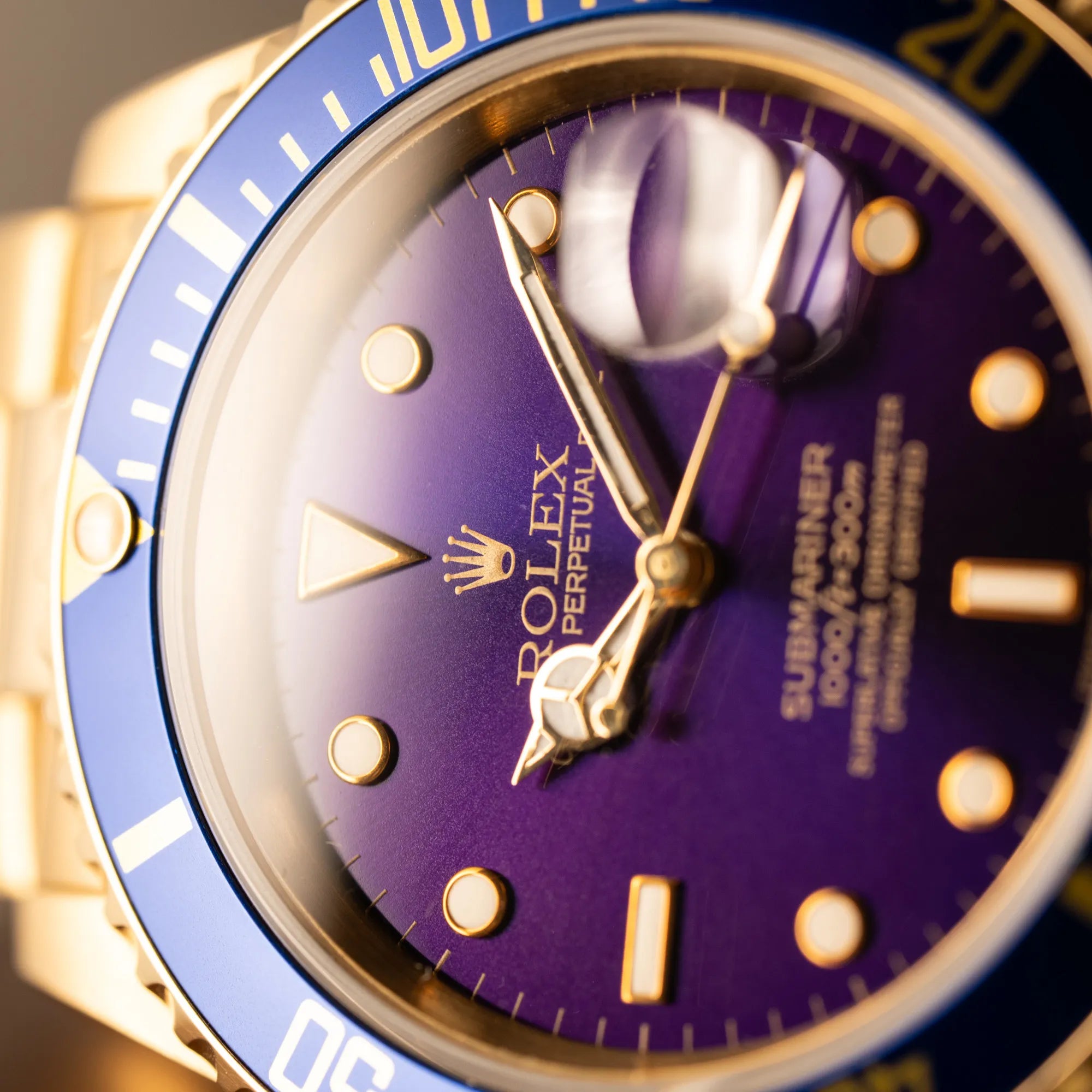 Makro-Aufnahme der Rolex Submariner Date 16618 aus 18Karat Gelbgold mit blauer Lünetten-Einlage und einem sich von BLAU zu LILA verfärbtem Purple-Zifferblatt