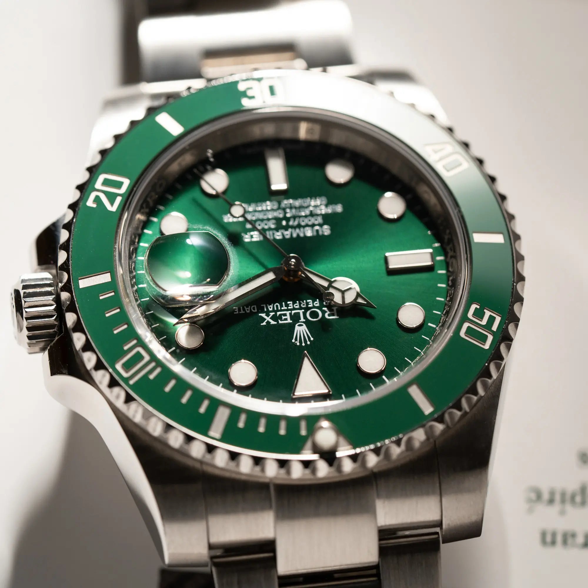 Nahe Produktfotografie der Rolex Submariner Date 116610LV mit dem Nickname "Hulk" mit grünem Zifferblatt und grüner Lünette in einem sehr guten Zustand mit Fokus auf der Lünette bei 4 Uhr