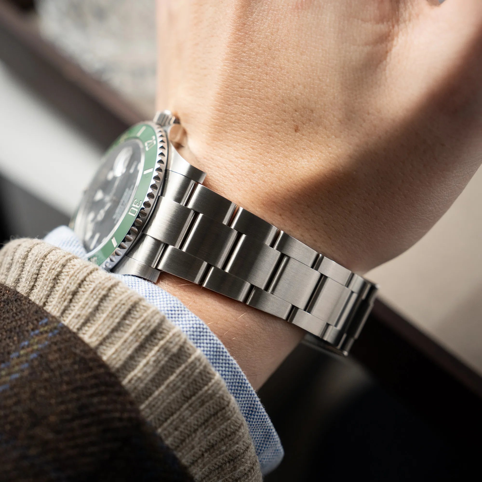 Mann präsentiert das neue Oyster Stahlband der Rolex Submariner Date Starbucks 126610LV Mark 2 aus 2025 mit der typischen grünen Cerachrom-Lünette an seinem Handgelenk