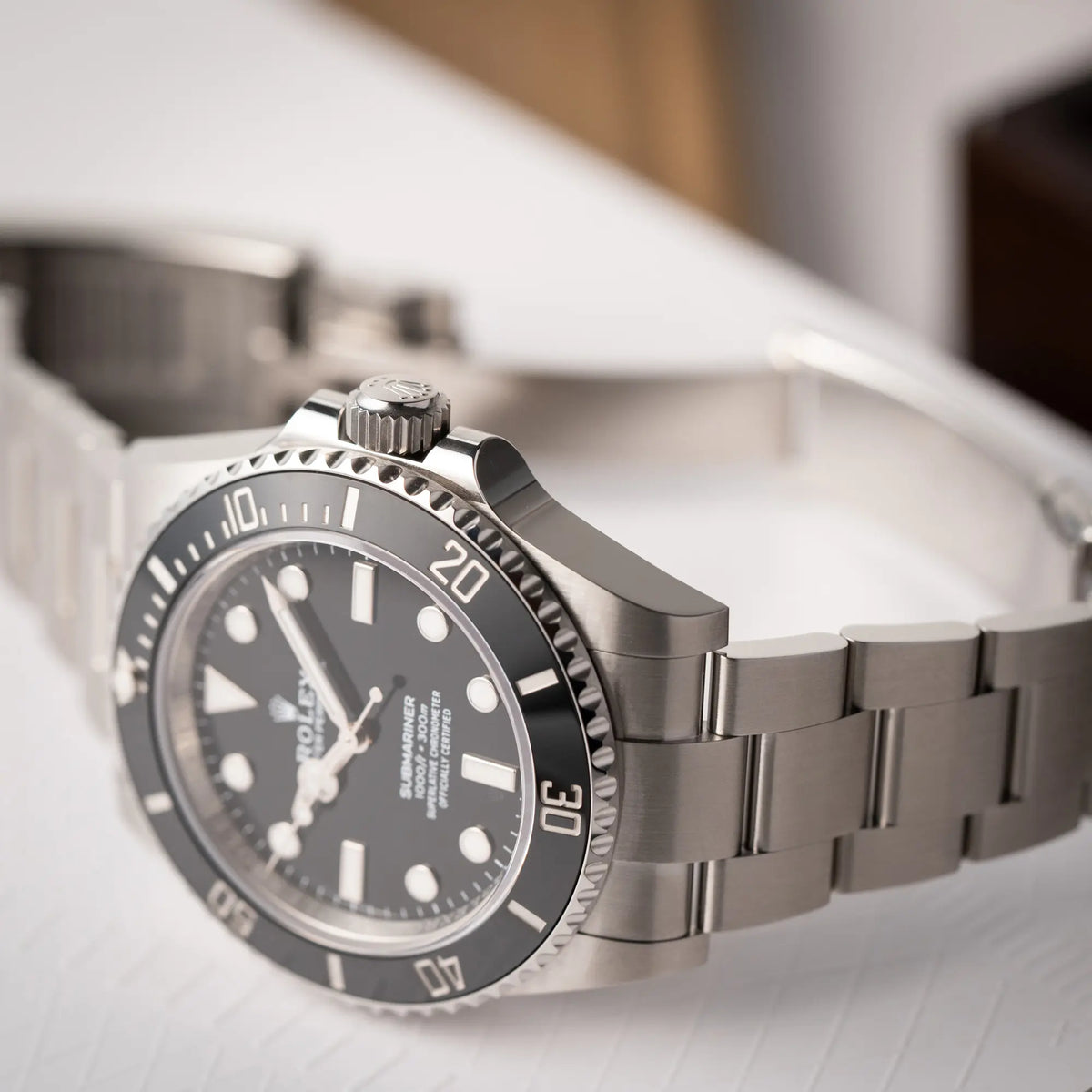 Produktfotografie der Rolex Submariner No Date der Referenz 124060 mit schwarzem Zifferblatt und schwarzer Keramik-Lünette an einem Oytser-Stahlband im Neuzustand zeigt die Lünette, den Kronenschutz und einen Bandanstoß