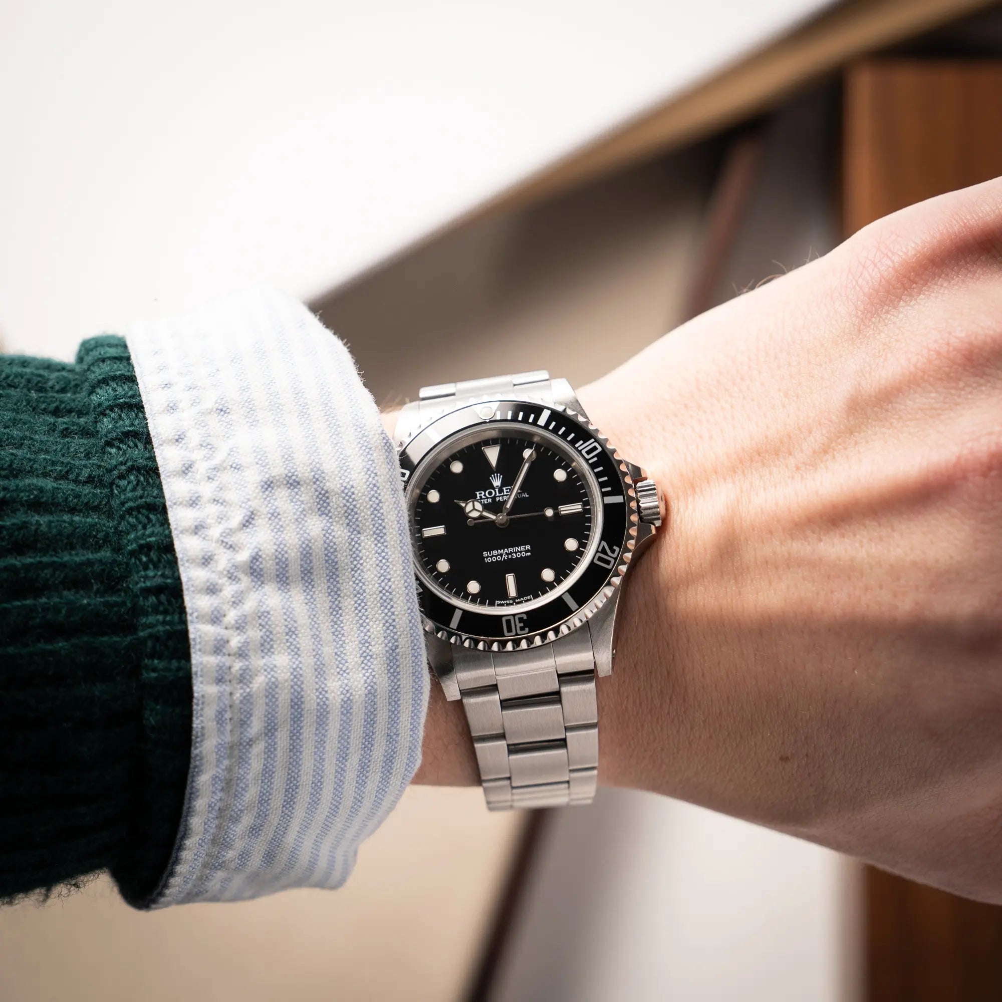 Mann trägt die Rolex Submariner No Date 14060M mit schwarzem Zifferblatt und der klassischen schwarzen Aluminium-Lünette an seinem Handgelenk