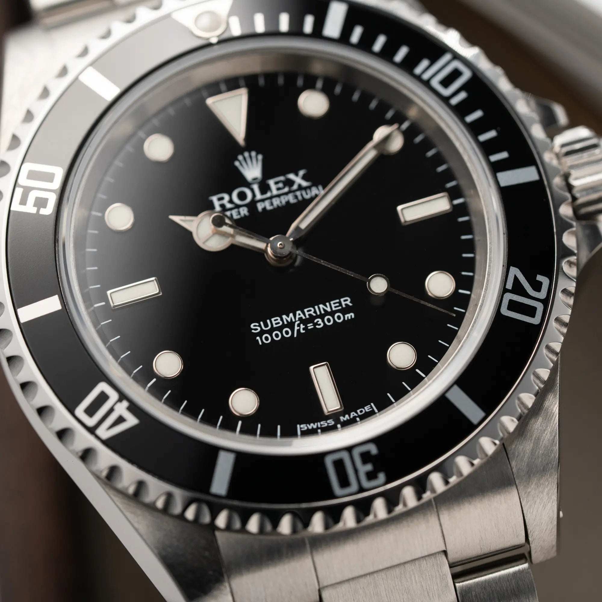 Detailaufnahme der Rolex Submariner No Date 14060M mit schwarzem Zifferblatt und der klassischen schwarzen Aluminium-Lünette mit Fokus auf dem Submariner 1000ft=300m Schriftzug