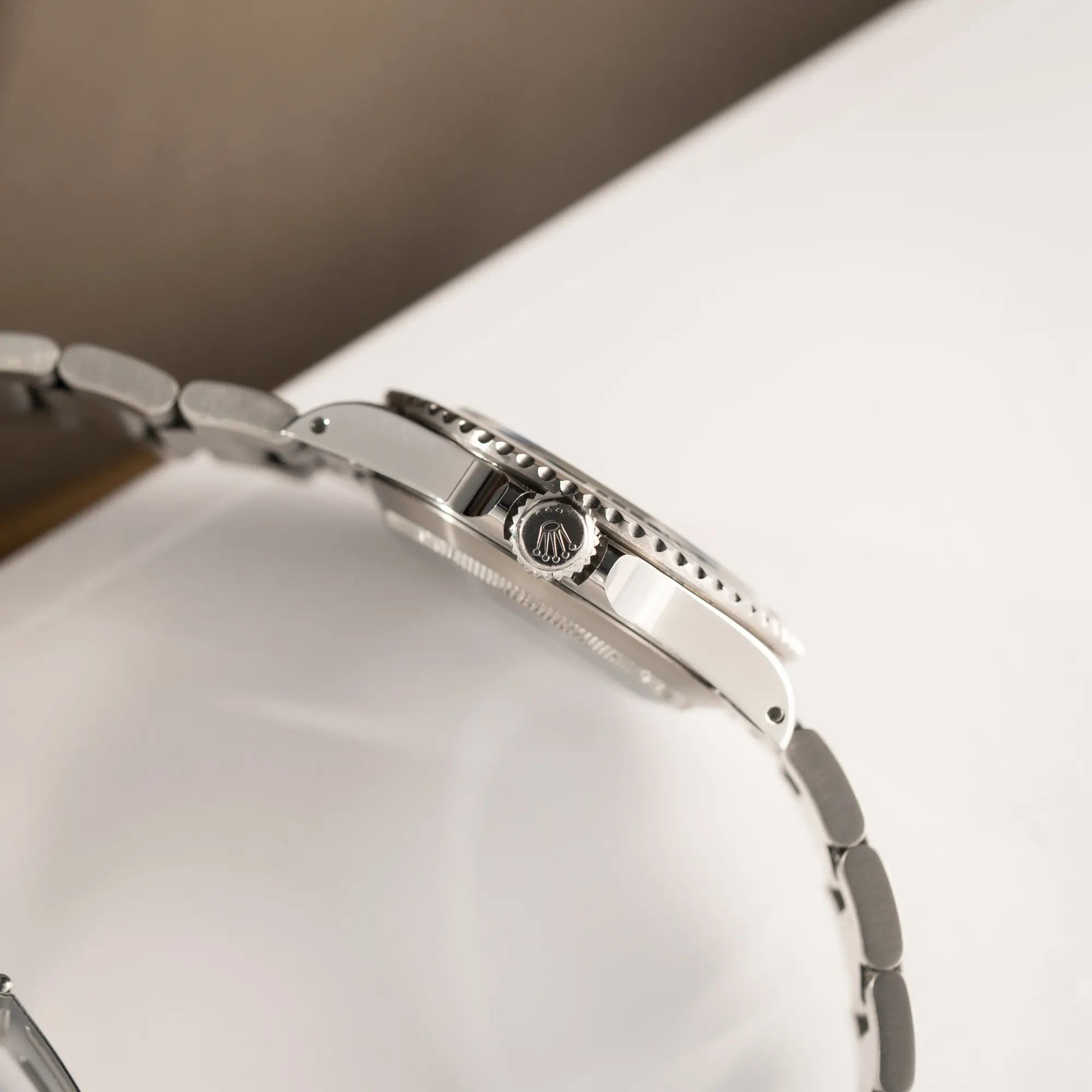 Produktfotografie zeigt die Aufzugskrone der Rolex Submariner No Date 14060M mit schwarzem Zifferblatt und der klassischen schwarzen Aluminium-Lünette 