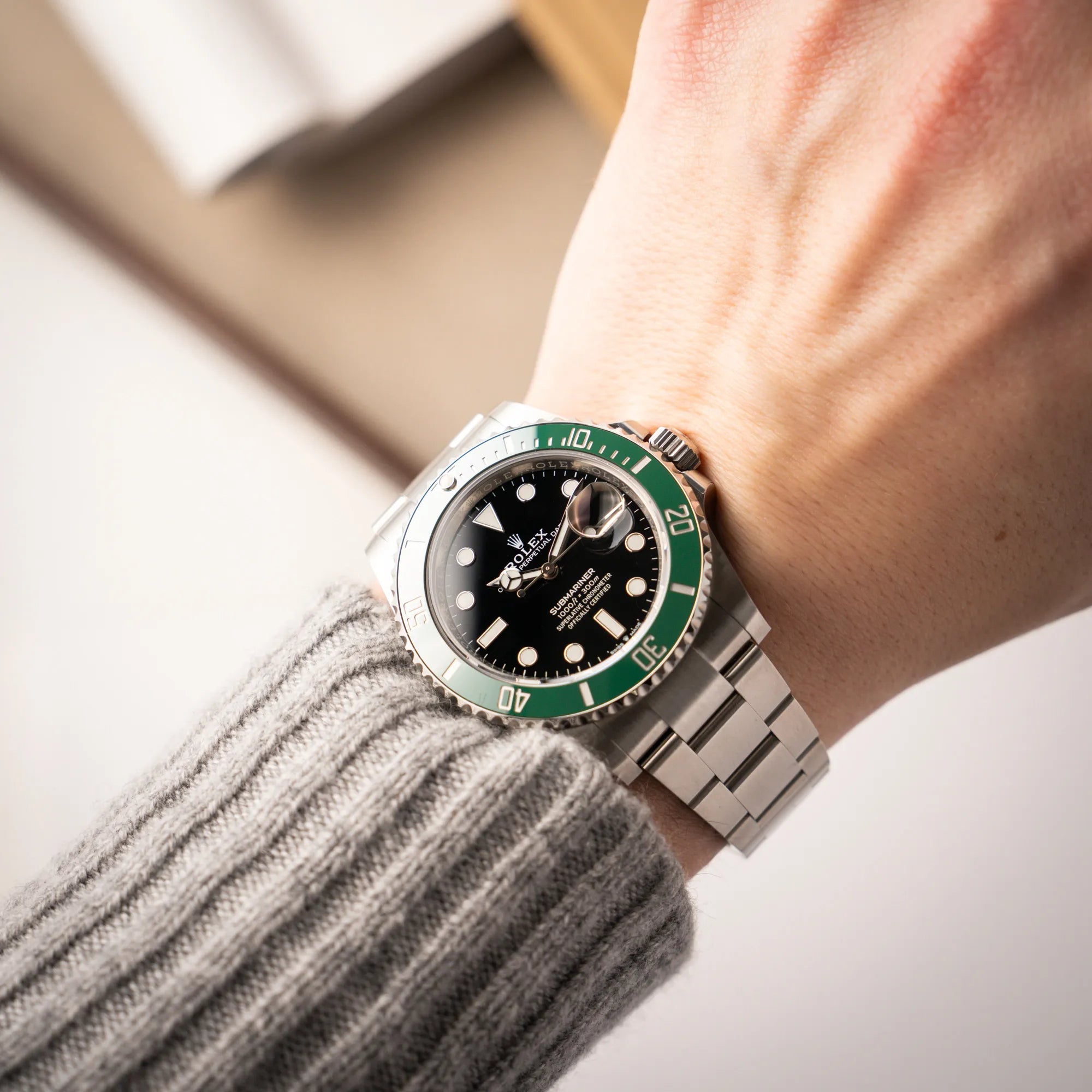 Mann trägt die Rolex Submariner Date "Starbucks" der Referenz 126610LV mit der modelltypischen grünen Keramik-Lünette, die im Kontrast zu dem schwarzen Zifferblatt steht, an seinem Handgelenk