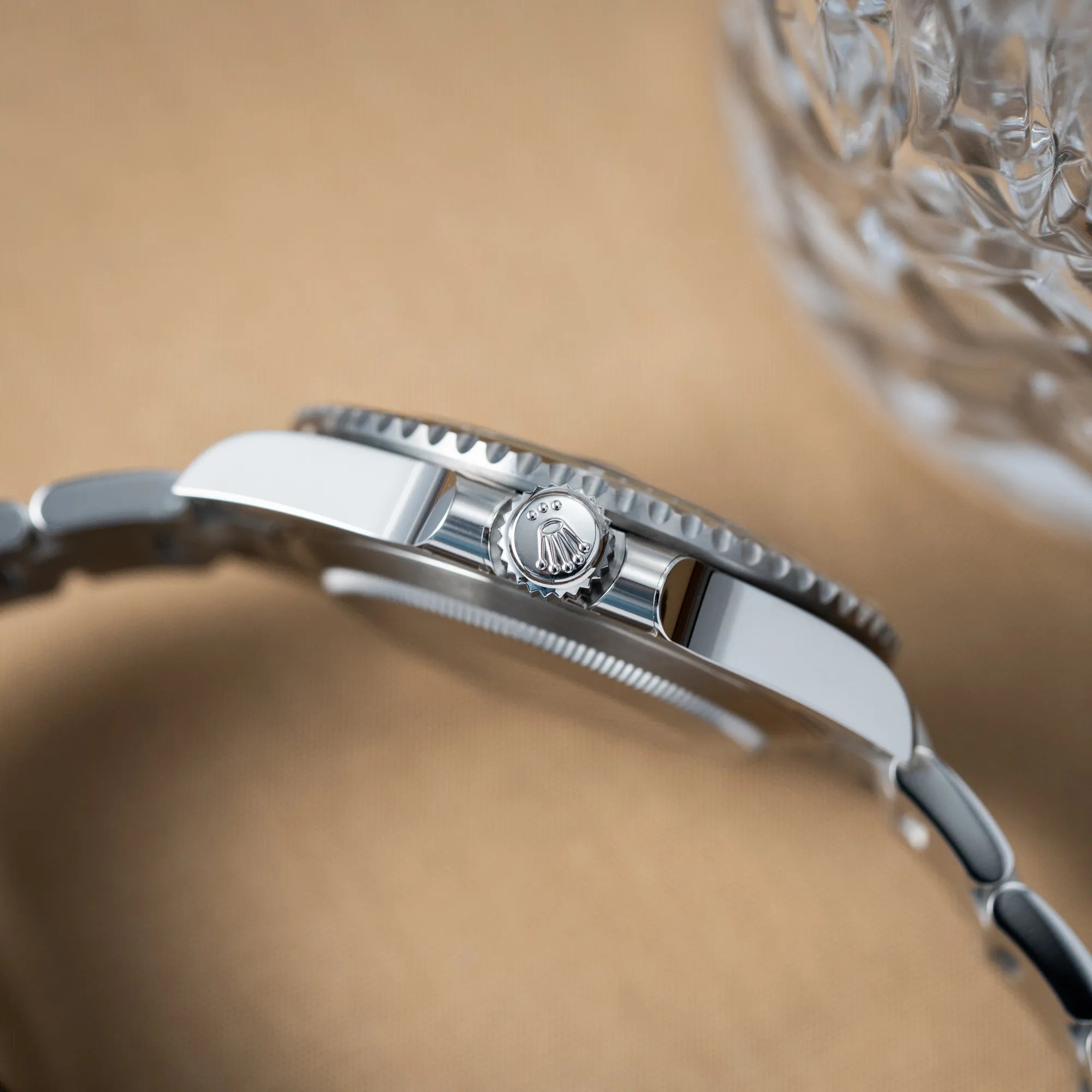 Seitliche Gehäuseflanke mit Blick auf die Aufzugskrone der Rolex Submariner Date "Starbucks" der Referenz 126610LV mit der modelltypischen grünen Keramik-Lünette, die im Kontrast zu dem schwarzen Zifferblatt steht