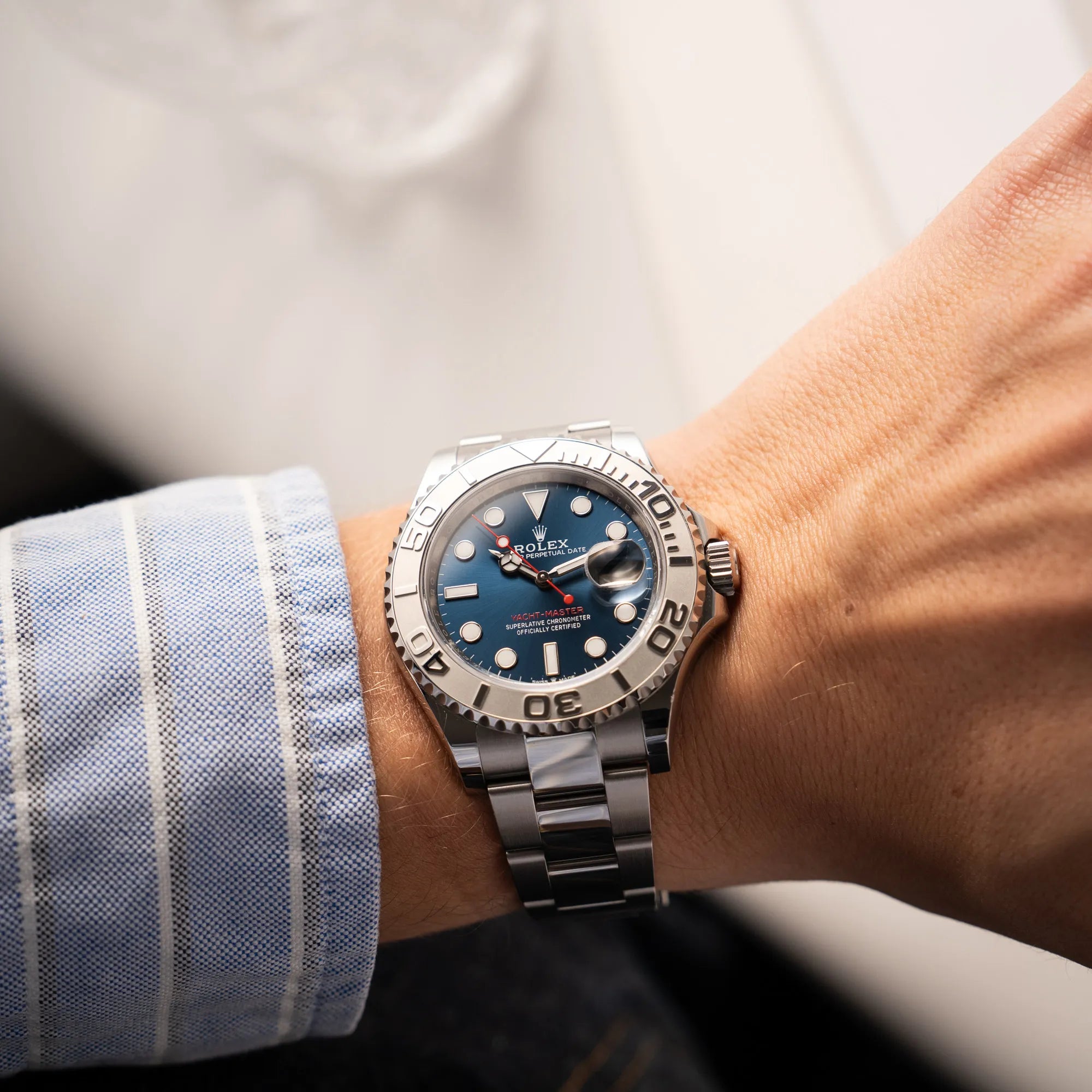 Wristshot mit der Rolex Yacht-Master 40 der Referenz 126622 mit der Platin-Lünette in der blauen Zifferblatt-Variante an einem Männerhandgelenk neben einem hellblauen Hemd