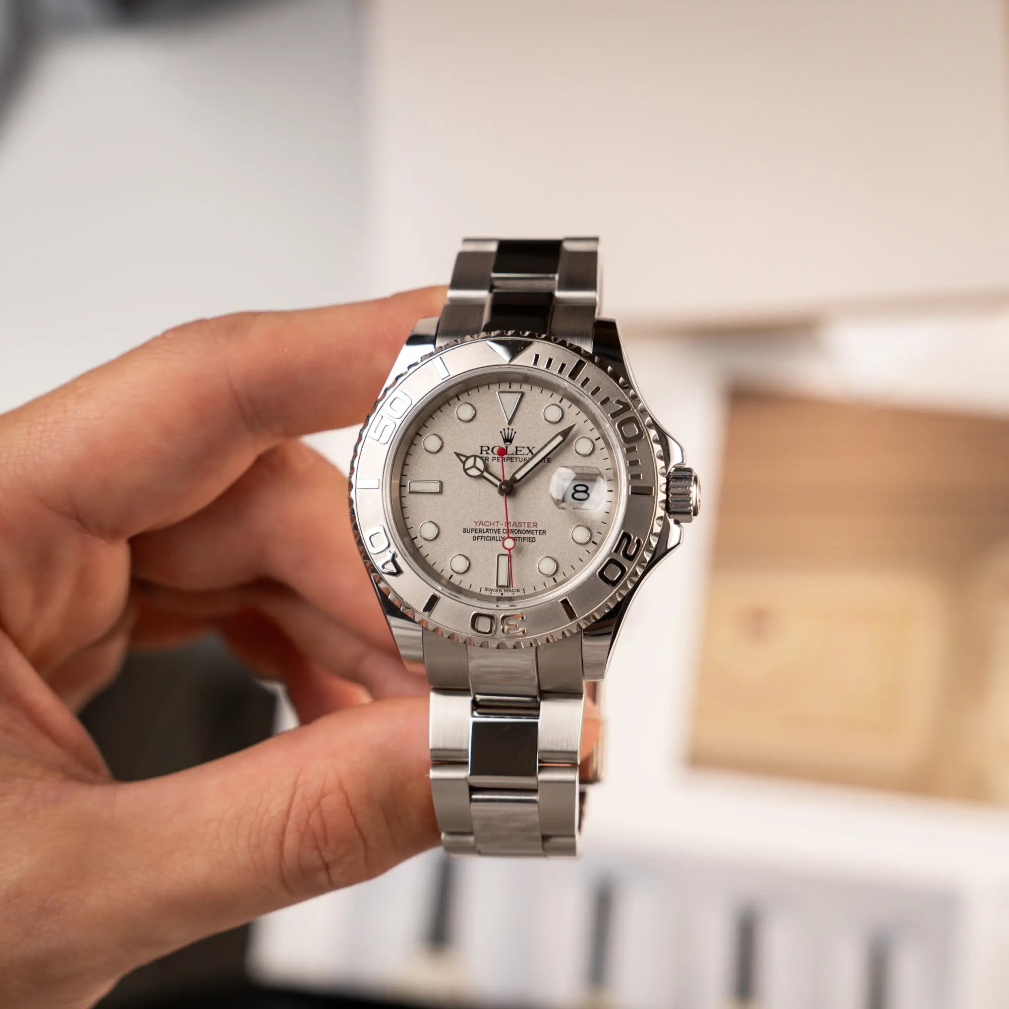 Mann präsentiert die Rolex Yacht-Master 40 Rolesium der Referenz 16622 mit dem silberfarbenen Platin-Zifferblatt und Platin-Lünette, sowie einem auffälligen in Rot gehaltenen Sekundenzeiger, in die Kamera 