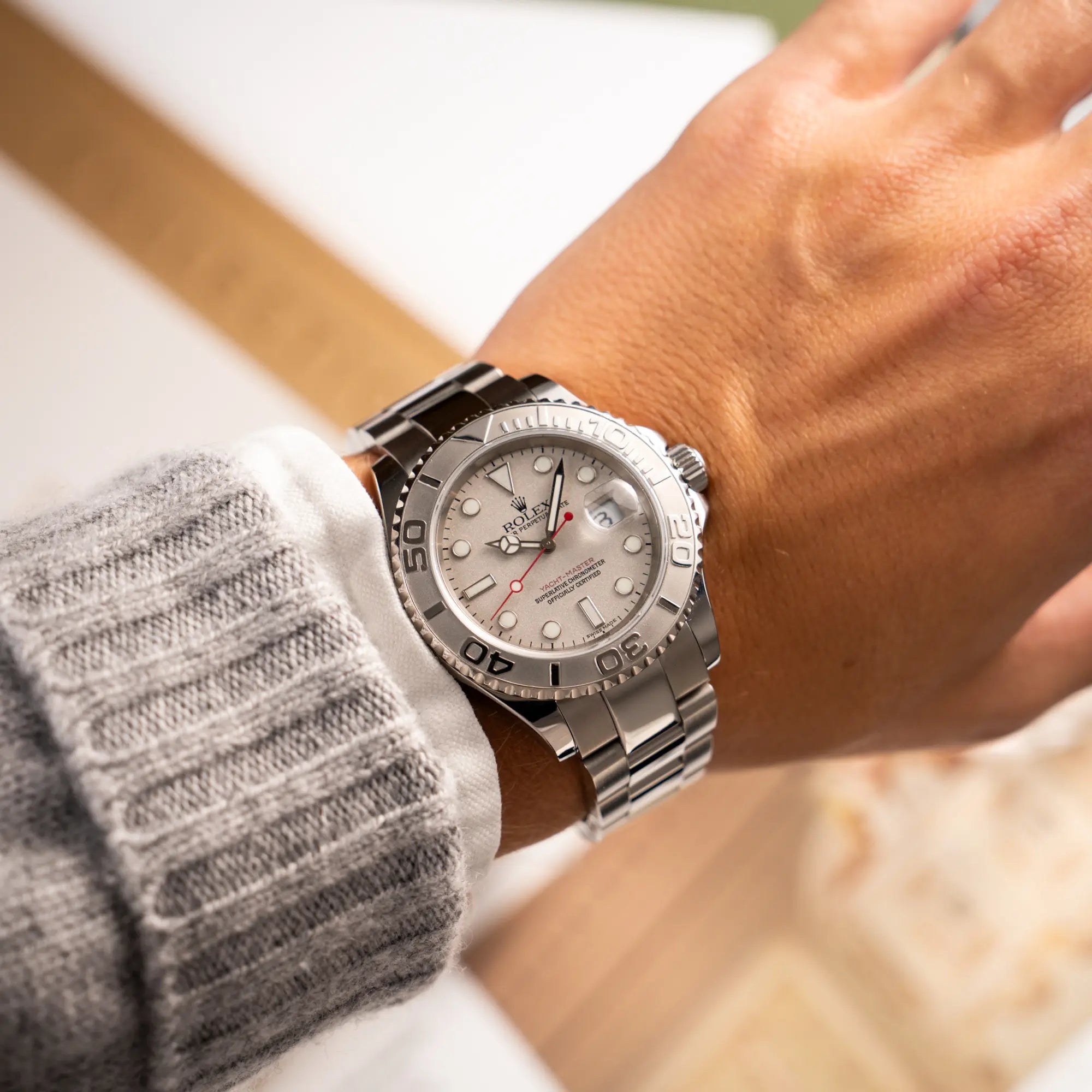 Mann trägt die Rolex Yacht-Master 40 Rolesium der Referenz 16622 mit dem silberfarbenen Platin-Zifferblatt und Platin-Lünette, sowie einem auffälligen in Rot gehaltenen Sekundenzeiger, an seinem Habdgelenk