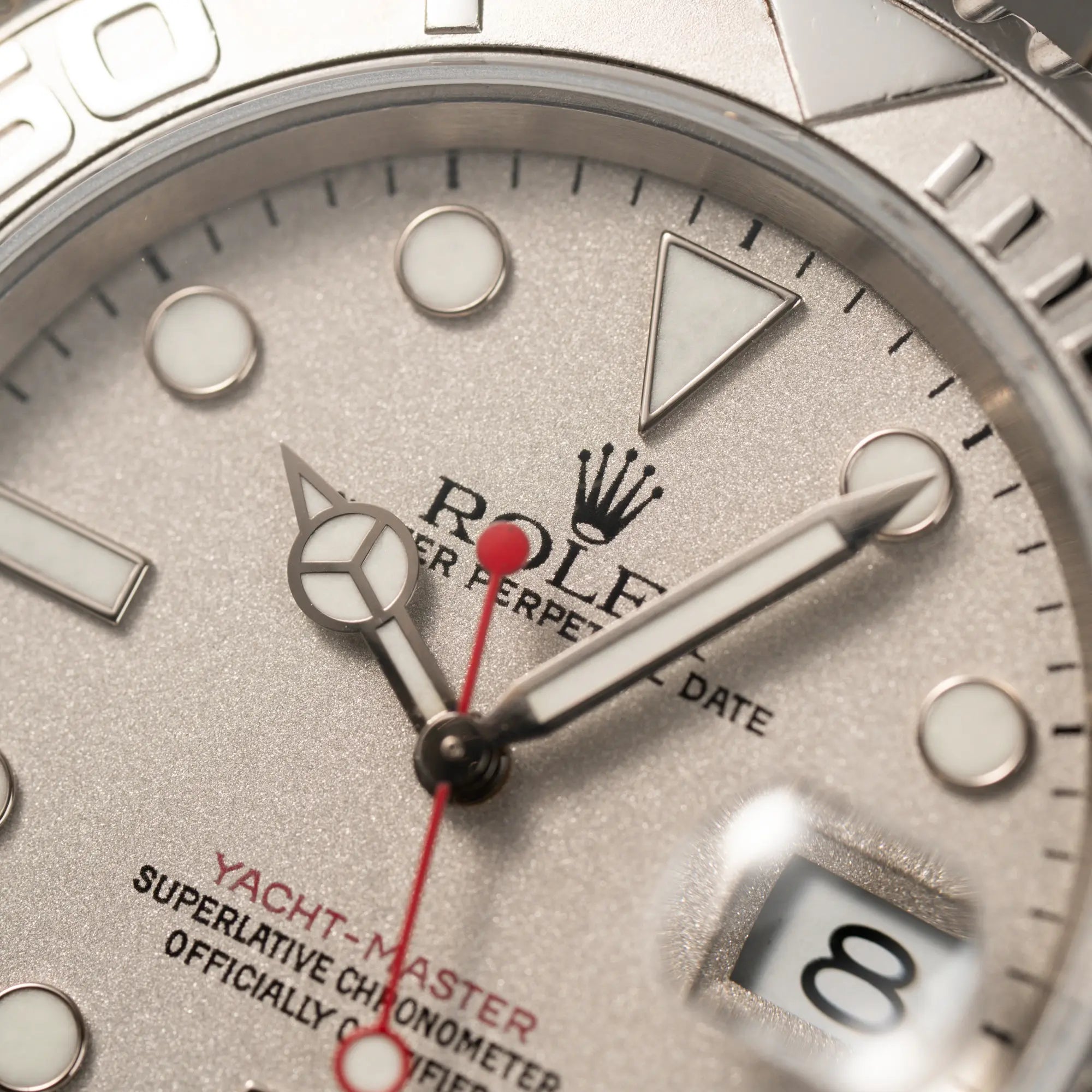 Makroaufnahme des Zifferblattes der Rolex Yacht-Master 40 Rolesium der Referenz 16622 mit dem silberfarbenen Platin-Zifferblatt und Platin-Lünette, sowie einem auffälligen in Rot gehaltenen Sekundenzeiger 