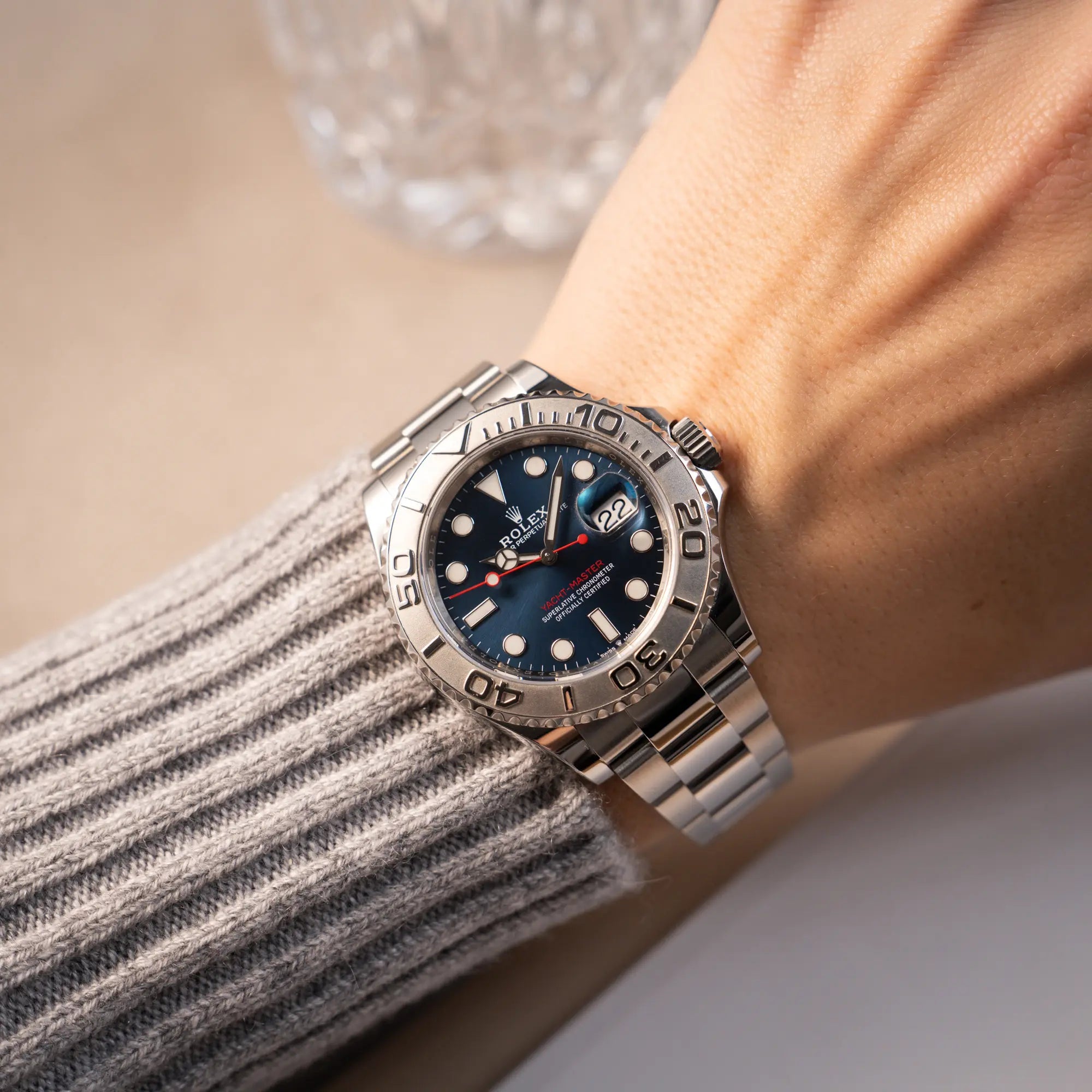 Mann in grauem Pullover trägt die Rolex Yachtmaster 40 der Referenz 126622 mit blauem Zifferblatt und der Rolesium-Lünette aus Platin