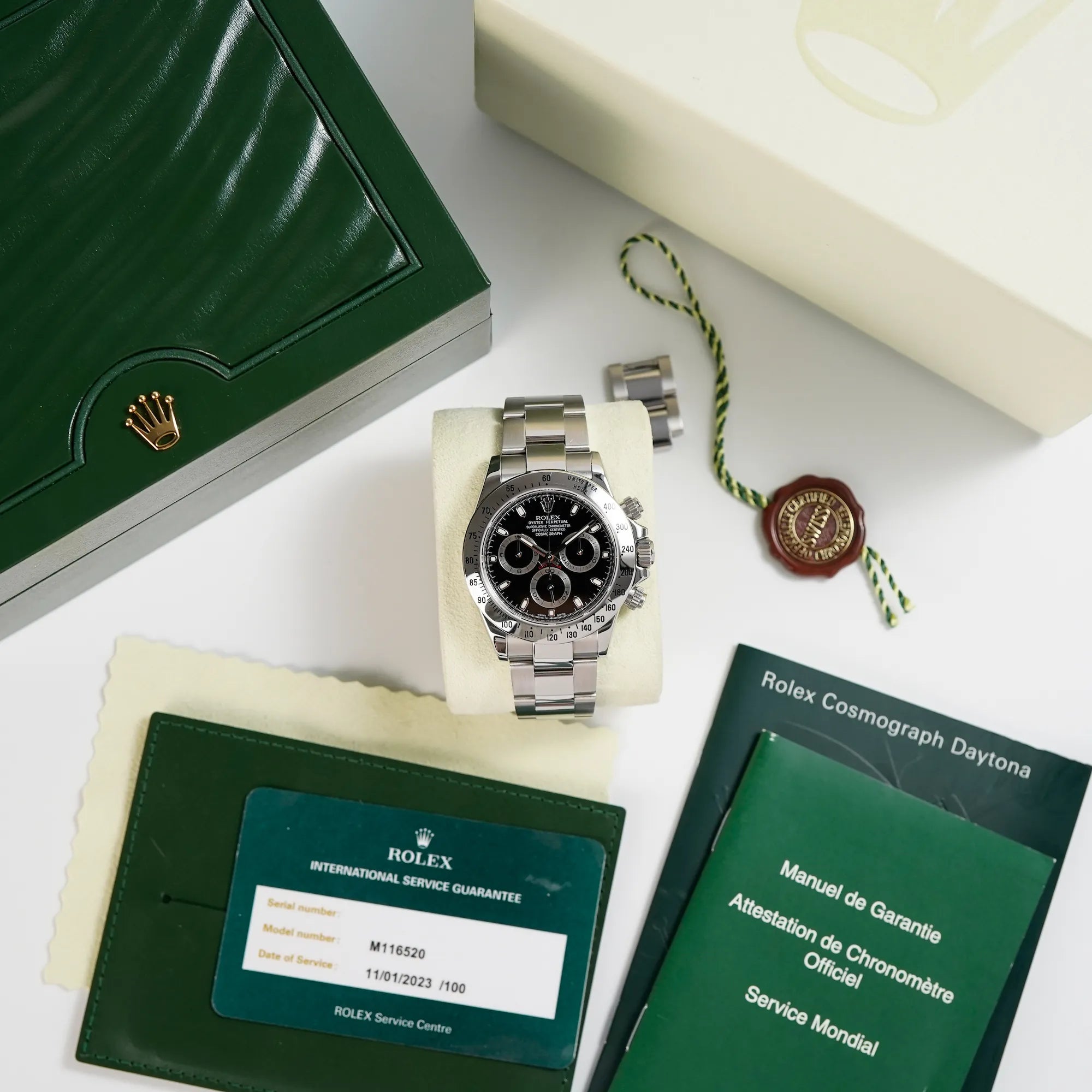 Rolex Cosmograph Daytona mit dem schwarzen Zifferblatt und der Edelstahl-Lünette zusammen mit dem Lieferumfang
