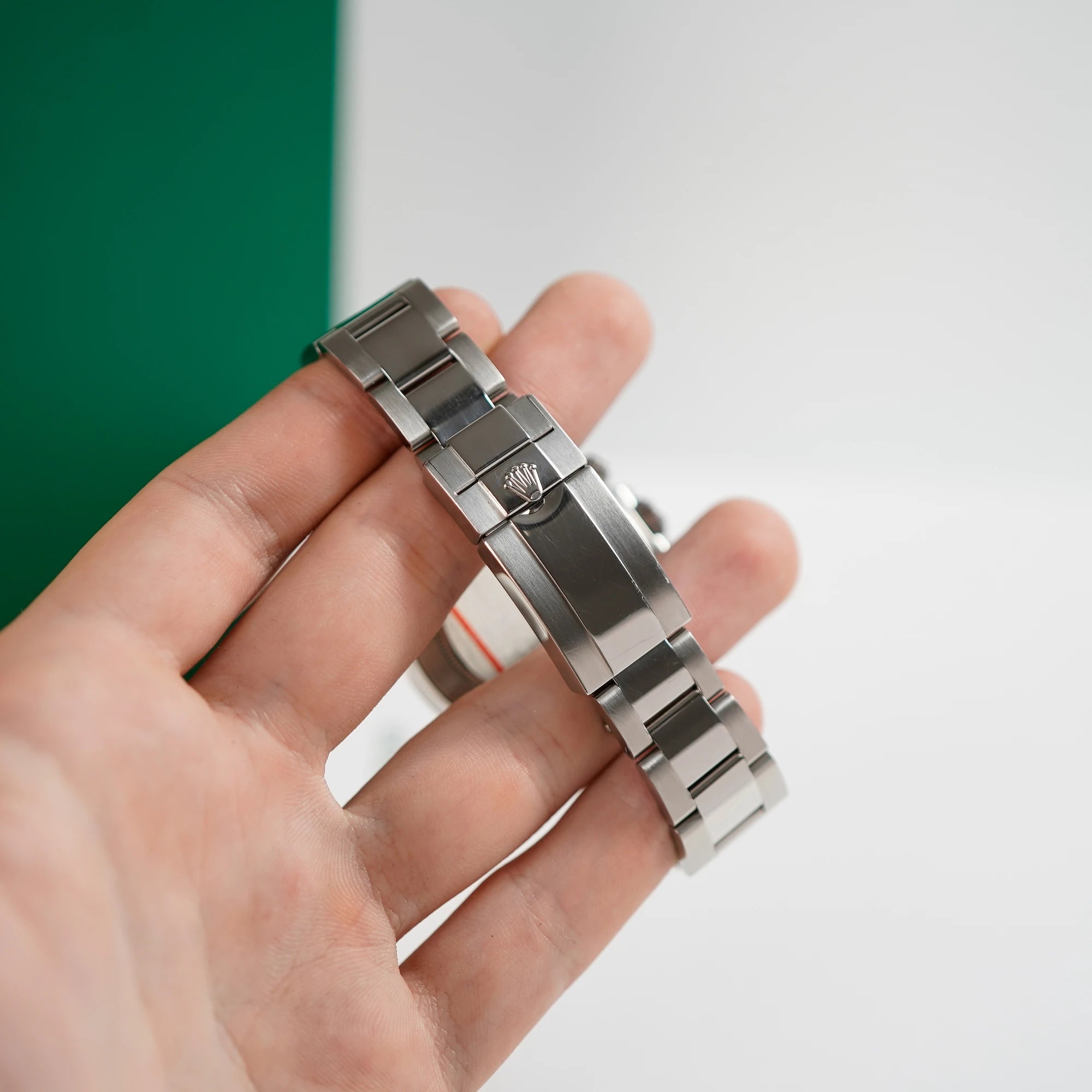 Mann hält die Rolex Cosmograph Daytona mit der Edelstahl-Lünette in seiner Hnad und präsentiert den hervorragenden Zustand des Bands und der Faltschliesse