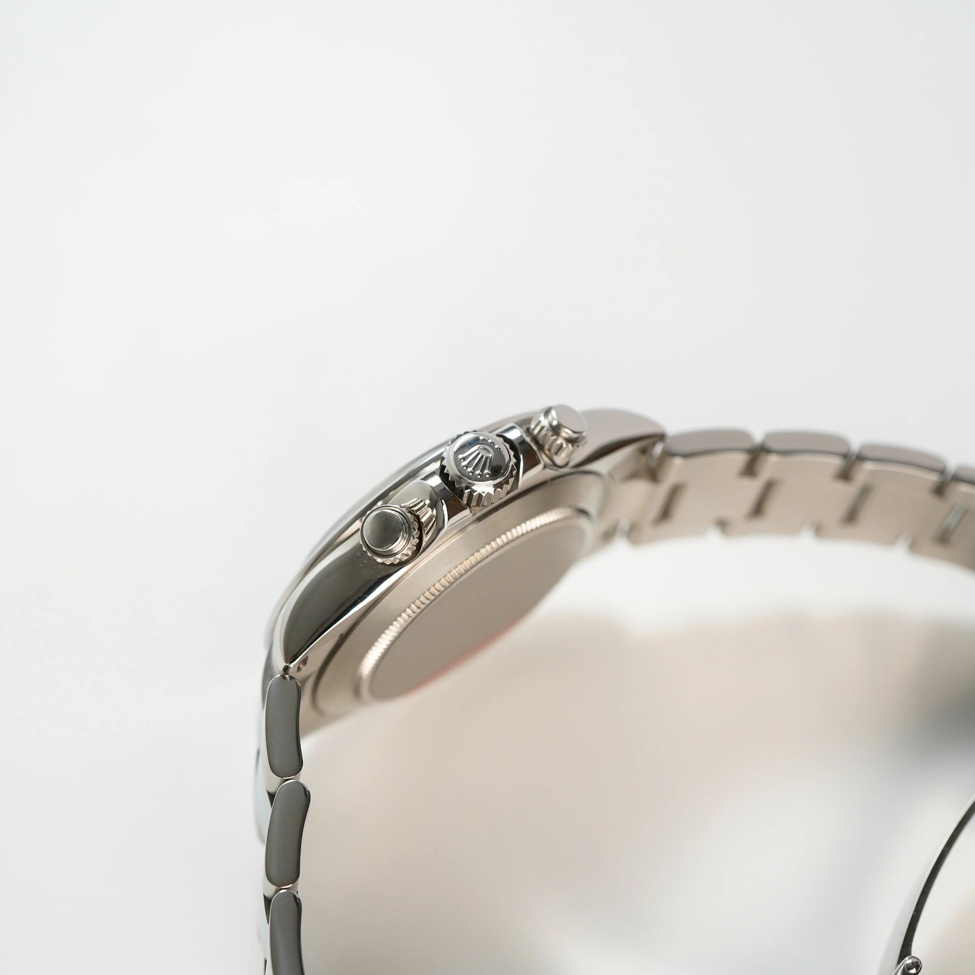 Seitliches Gehäuse mit Blick auf die Krone und Chronograph-Drücker der Rolex Cosmograph Daytona mit dem schwarzen Zifferblatt und der Edelstahl-Lünette