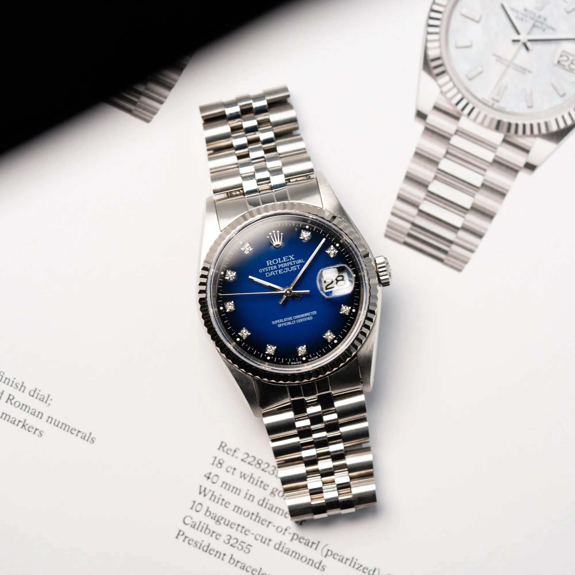 Produktfotgrafie der Rolex Datejust 36 mit einem sehr seltenen Degradé Diamond Zifferblatt, dass von Blau ins Schwarze verläuft, während die Ihr auf einem Rolex-Heft liegt
