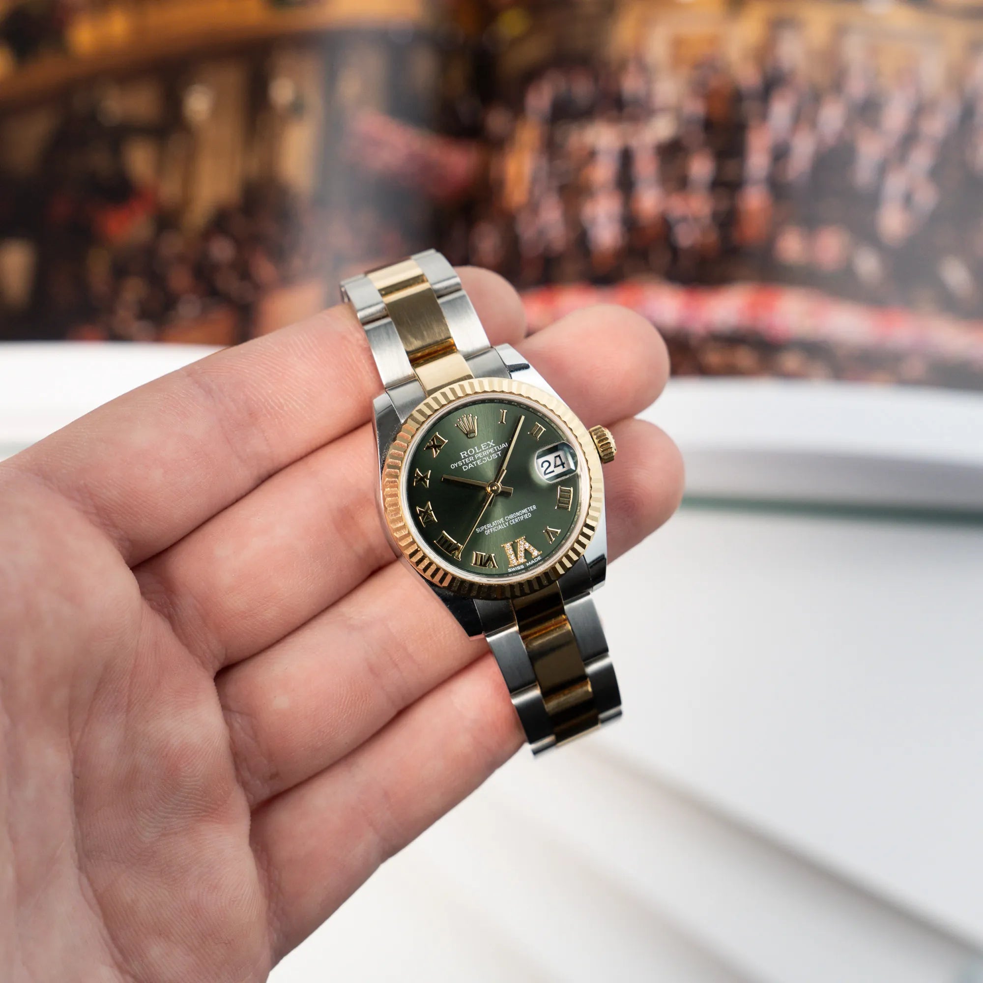 Mann hält die Rolex Datejust 31 mm für Ladies mit einem oliven Zifferblatt und einem diamantbesetzten Index in seiner Hand