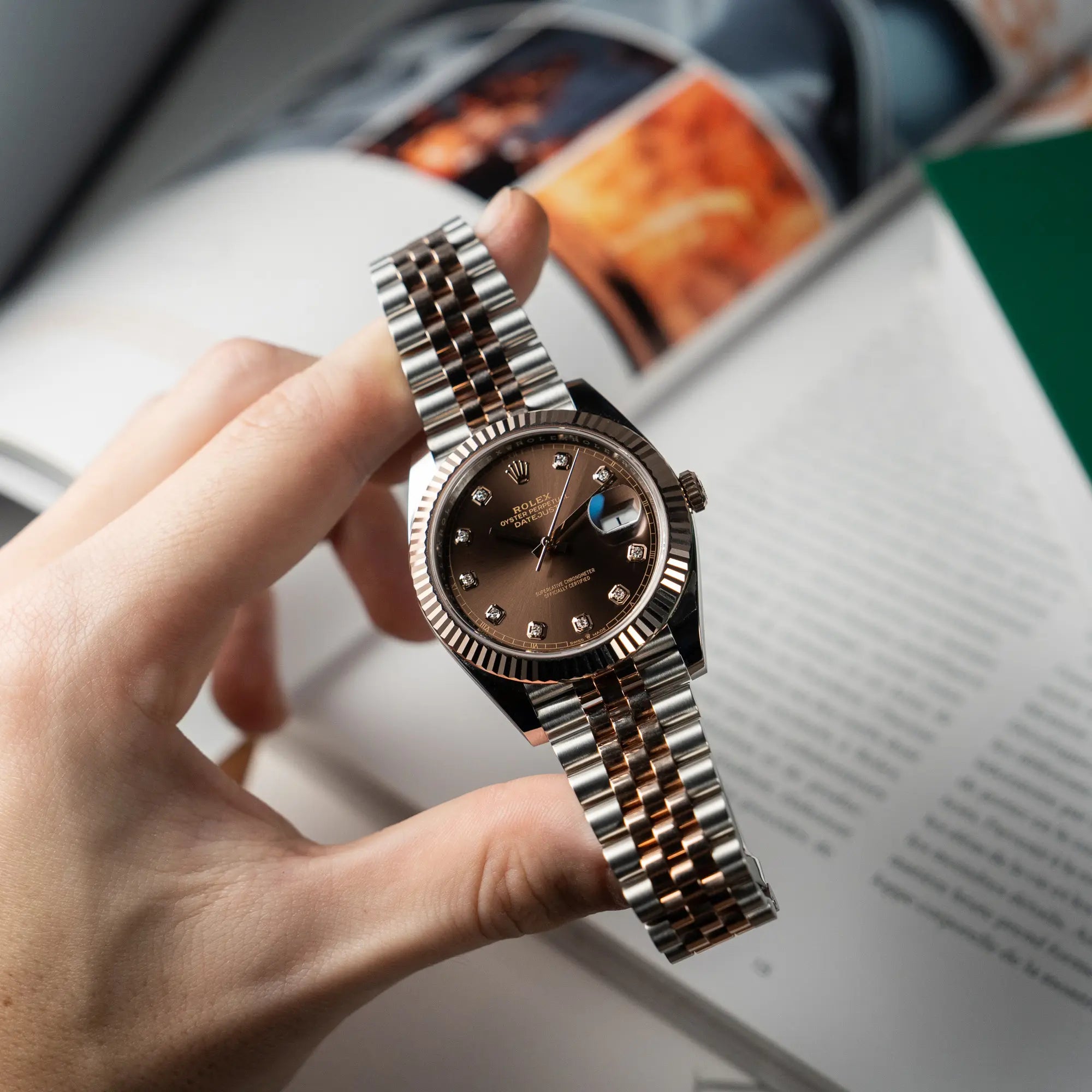 Mann hält die neue Rolex Datejust 41 in Stahl-Rosegold mit braunem Diamant-Zifferblatt in seiner Hand und präsentiert die Uhr in die Kamera