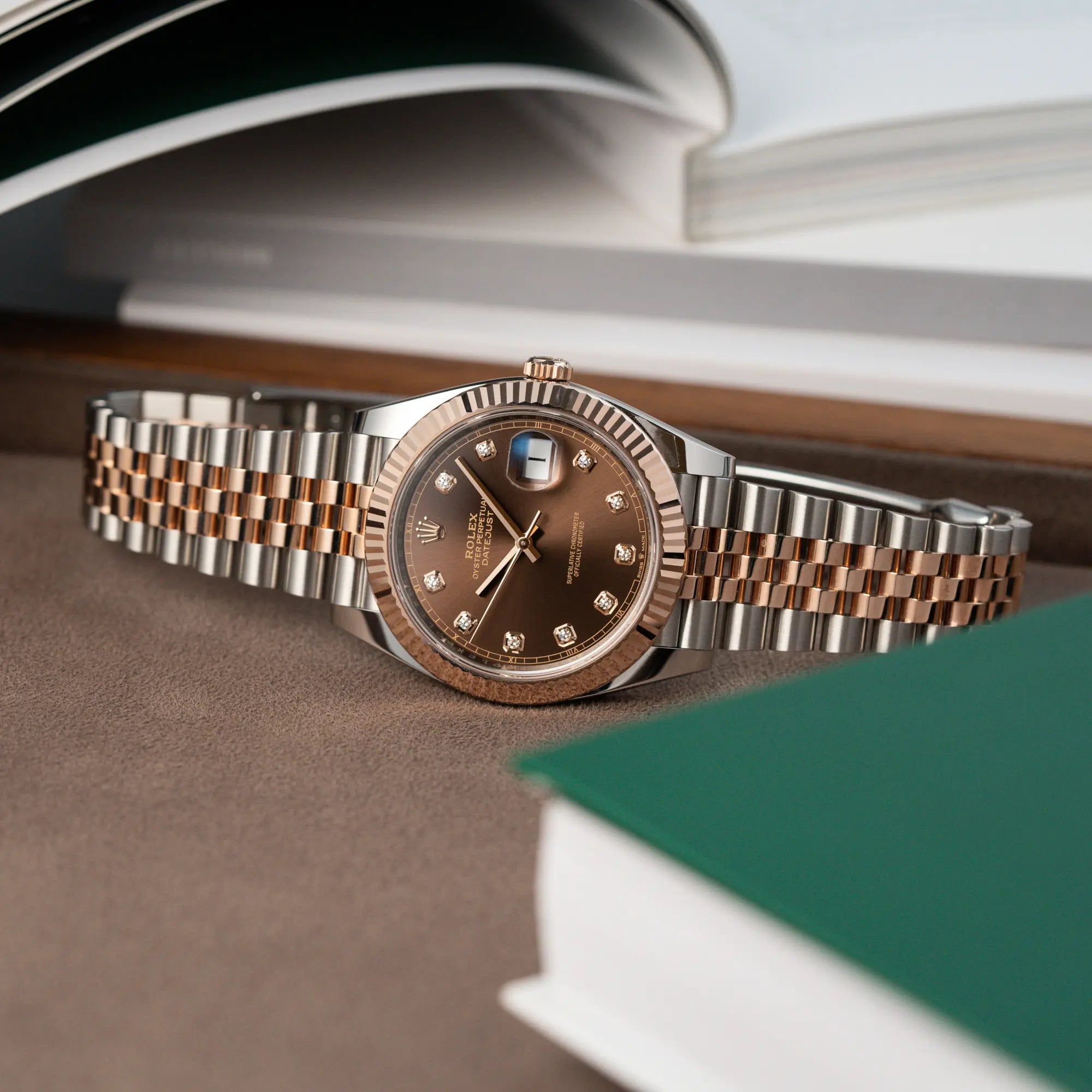 Produktfotografie der seitlich liegenden Rolex Datejust 41 in Stahl-Rosegold mit braunem Diamant-Zifferblatt