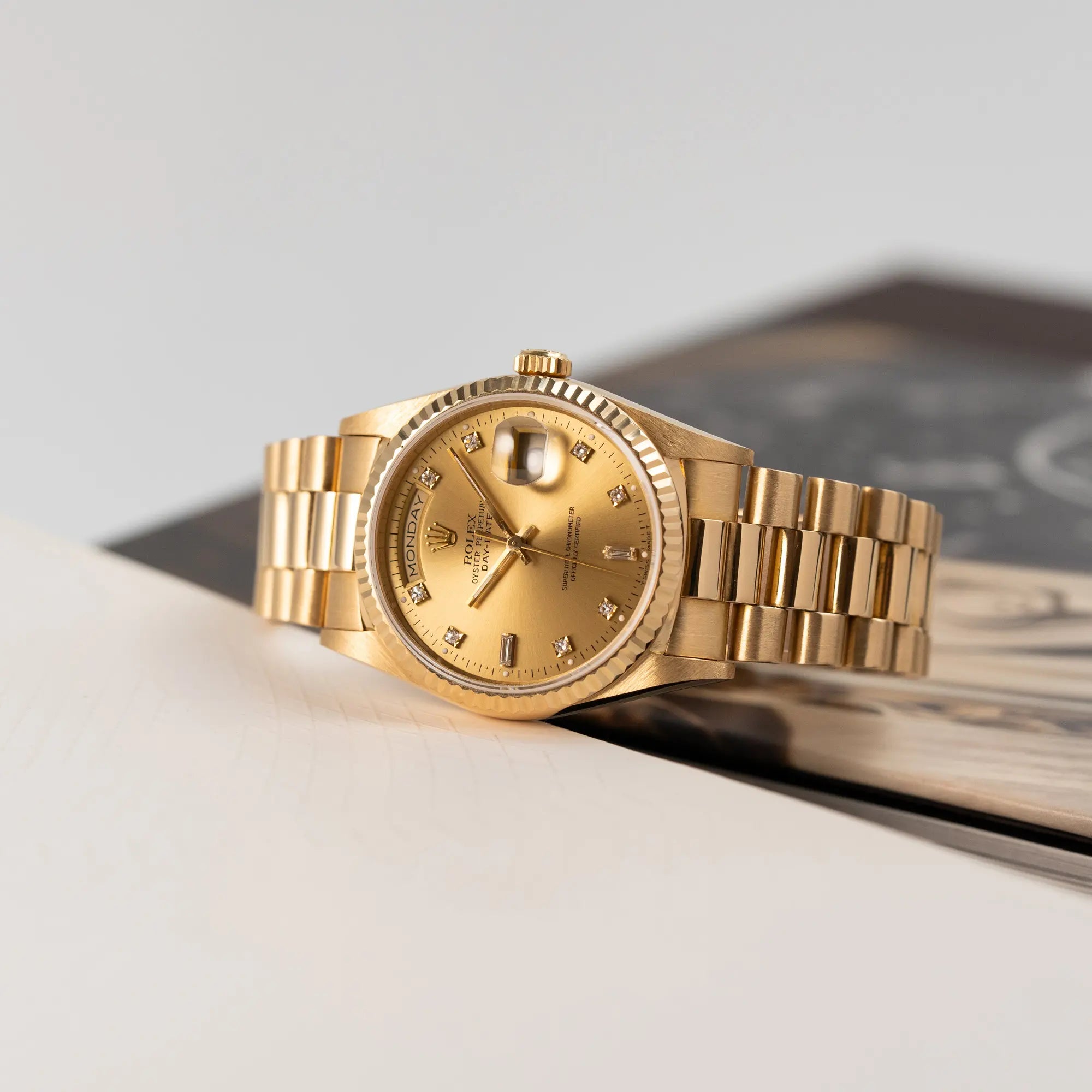 Produktfotografie der Rolex Day-Date 18238 in Gelbgold mit goldenem Zifferblatt und Diamant-Indizes am President-Armband, während die Uhr seitlich auf ihrem Gehäuse liegt