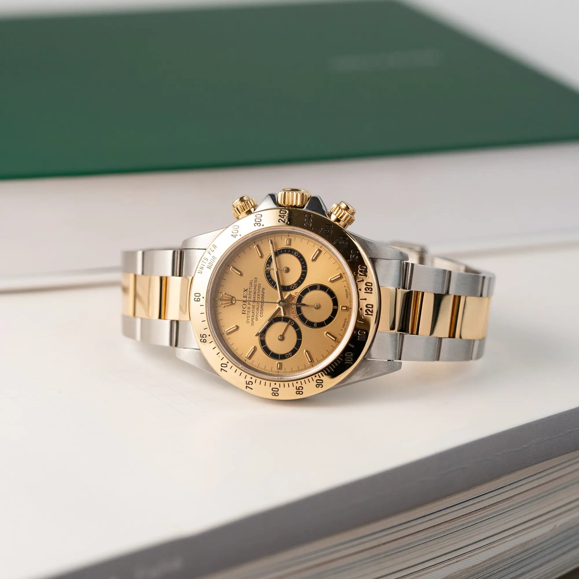 Produktfotografie der seitlich liegenden  Rolex Zenith Daytona in Stahl-Gold mit goldfarbenem Zifferblatt
